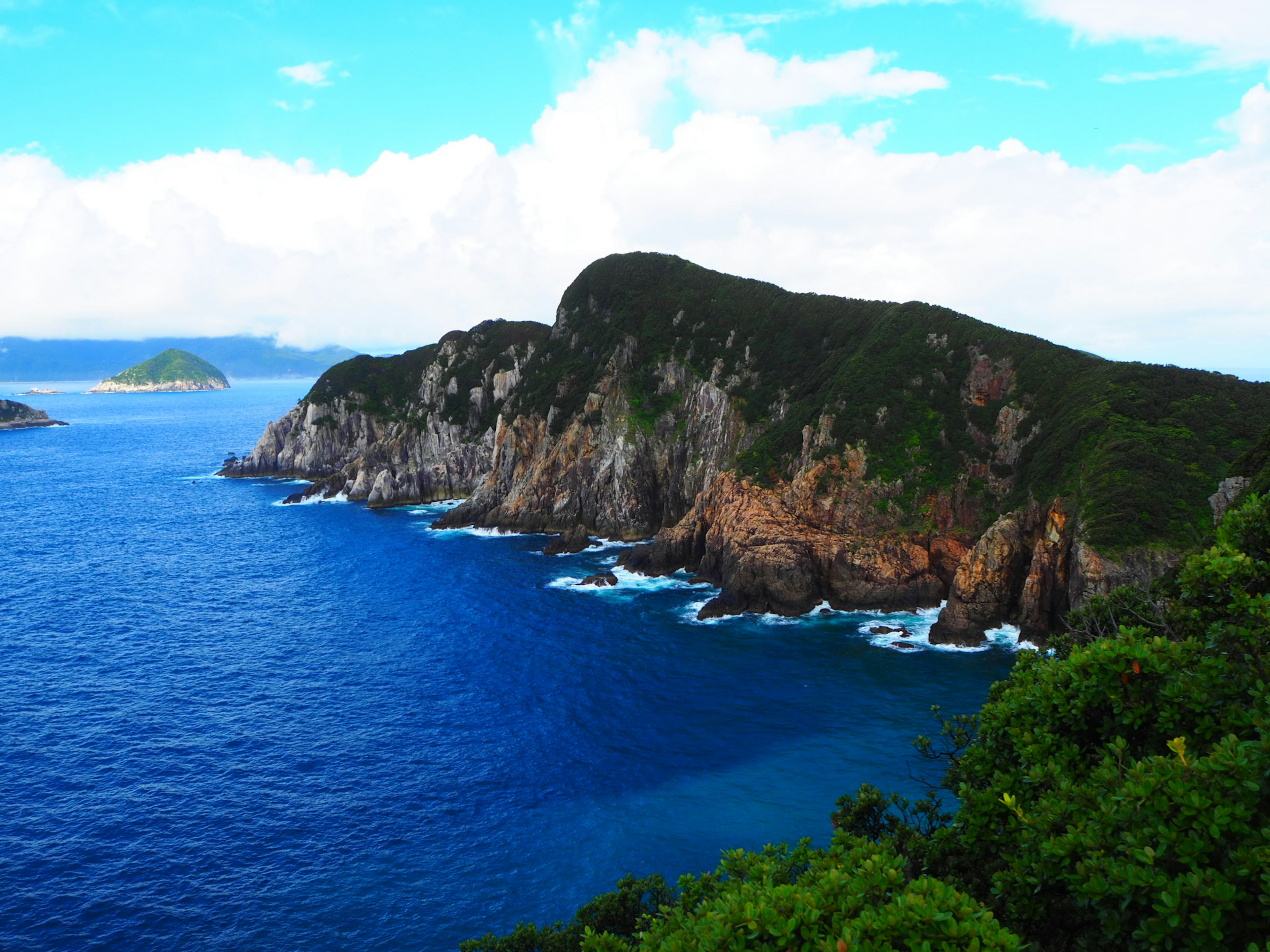 Lanskap pantai dengan tebing berbatu dan lautan biru cerah