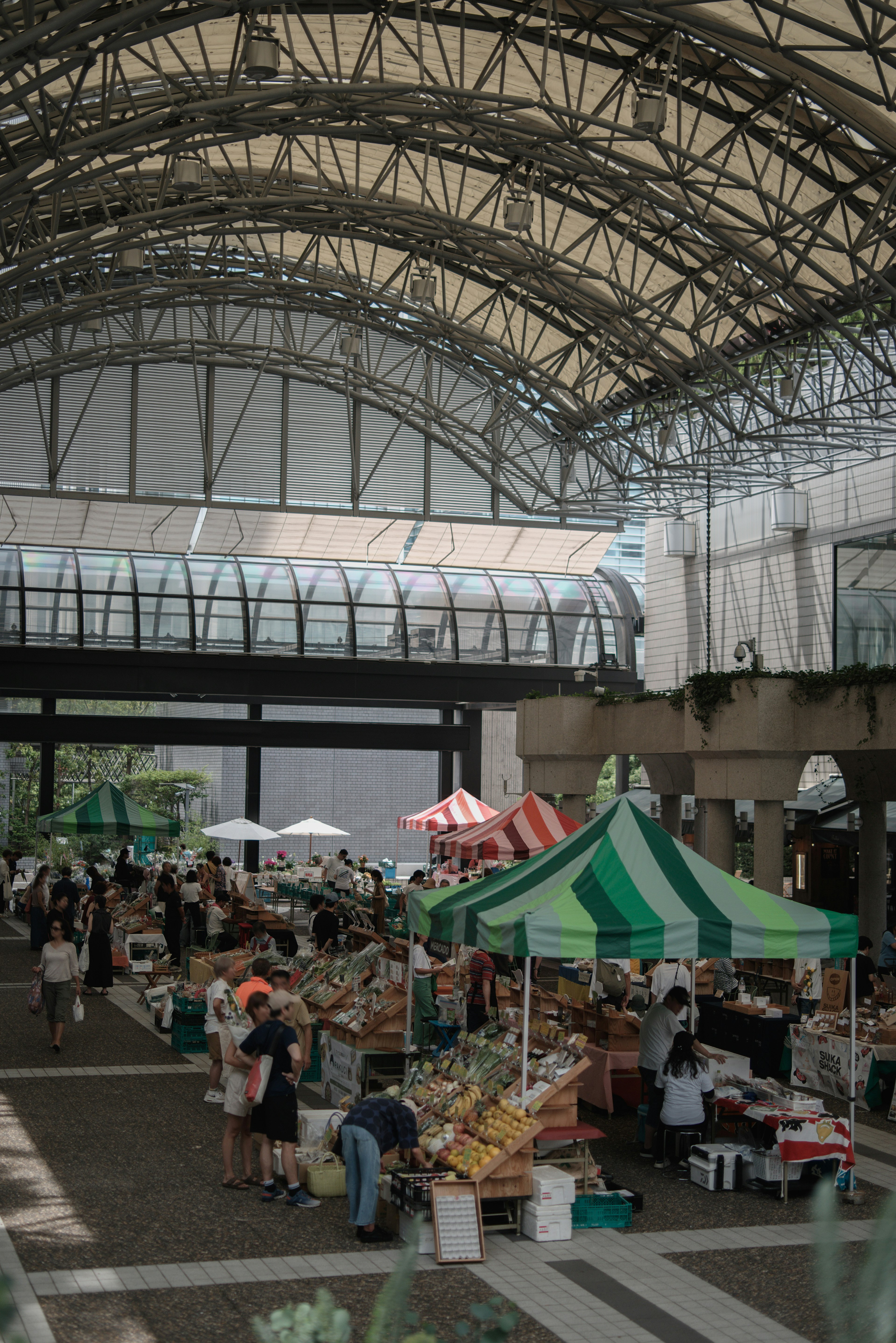 Indoor market scene featuring green and white tents bustling with people