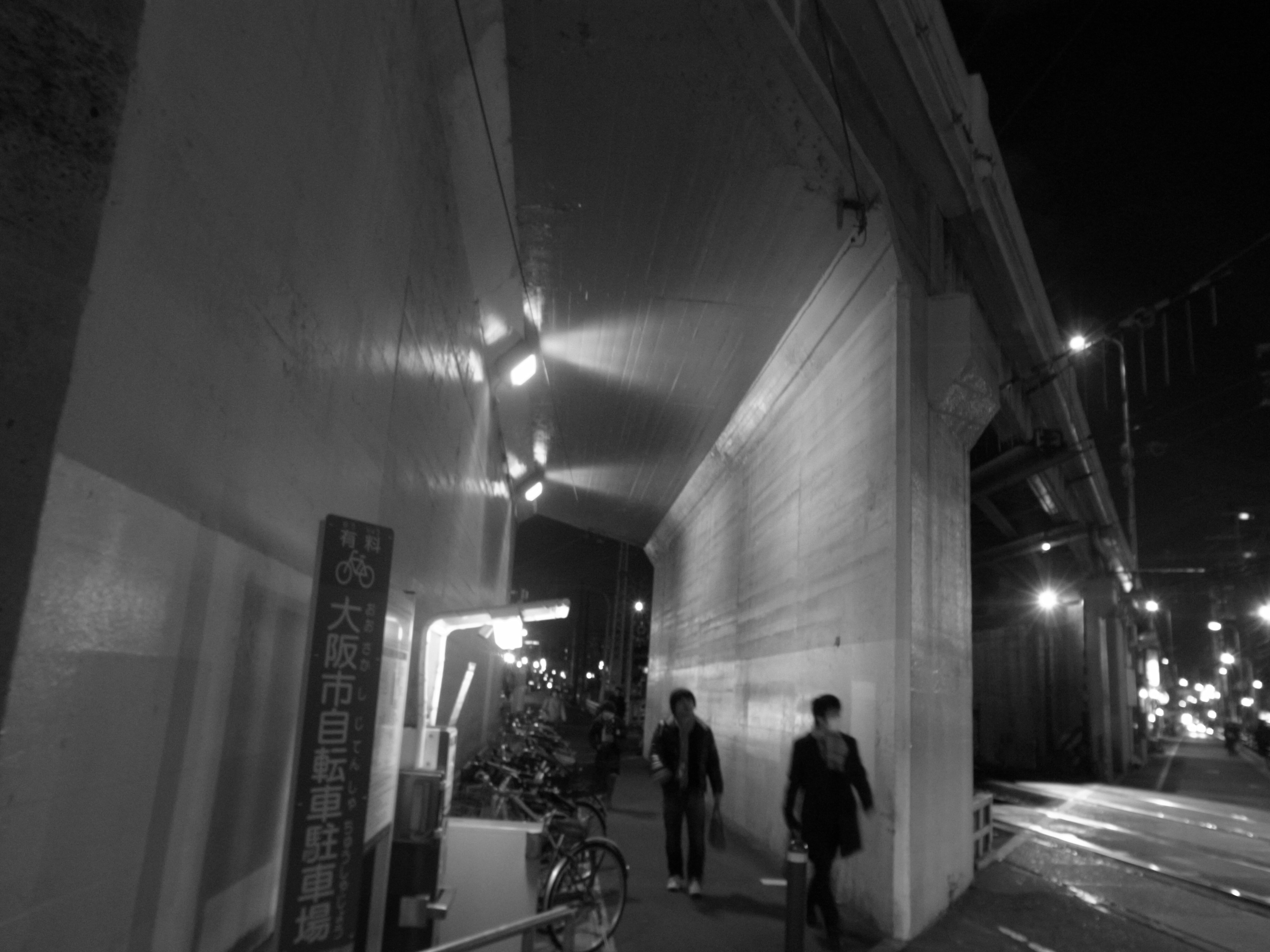 Two people walking in a city at night with bright streetlights