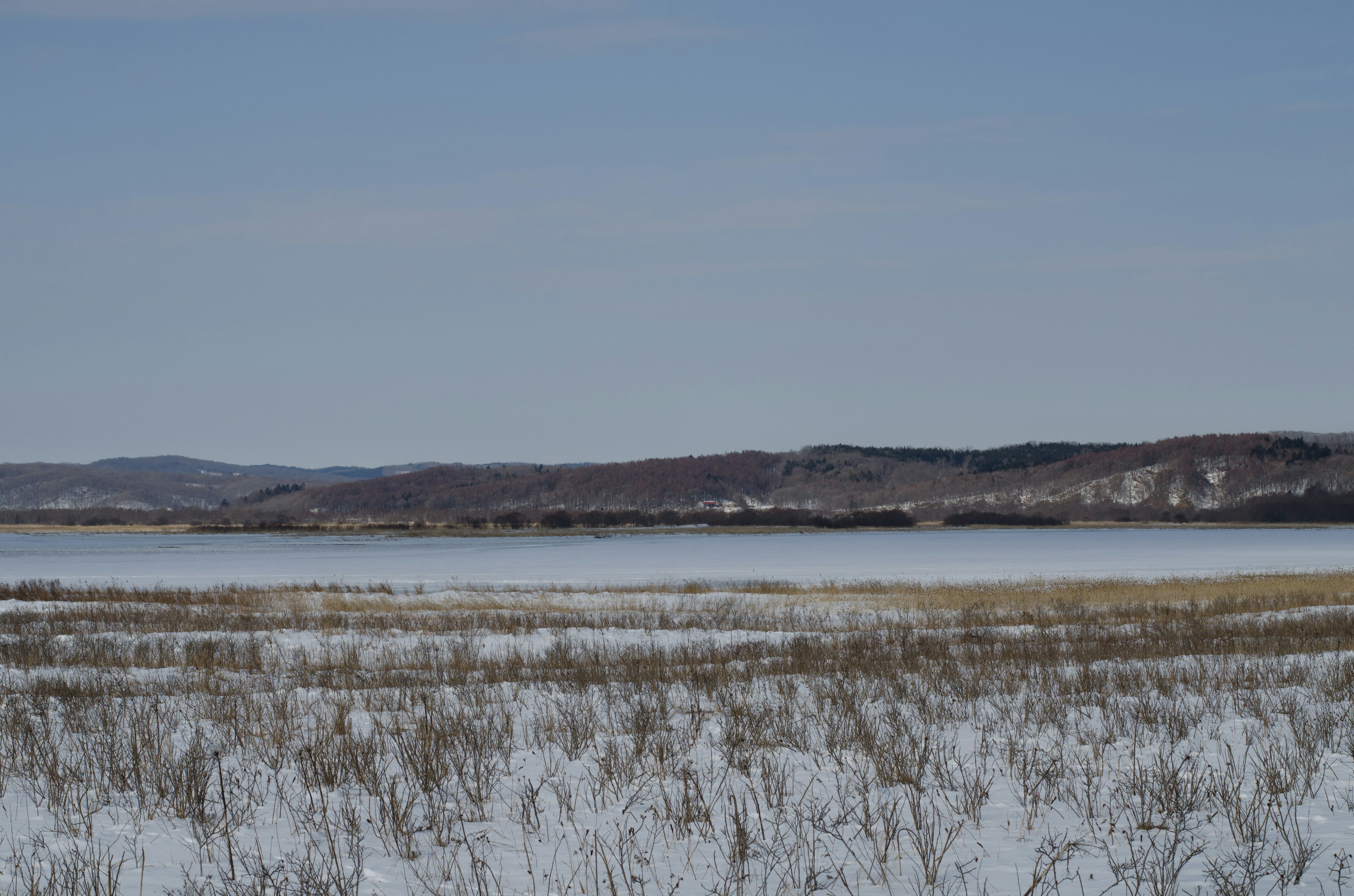 Prairie enneigée avec un lac tranquille et des collines lointaines