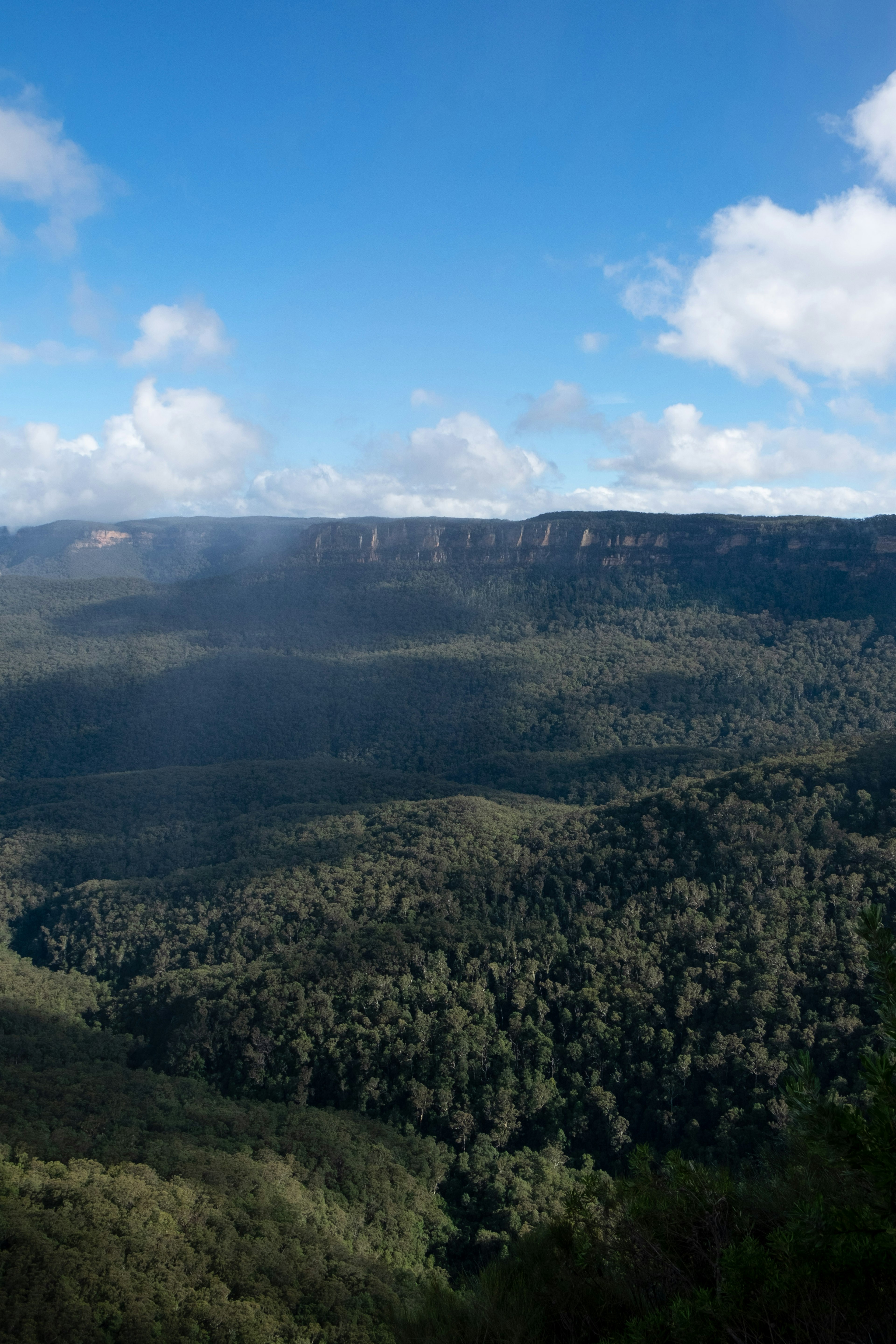 Vue pittoresque de montagnes verdoyantes sous un ciel bleu avec des nuages blancs