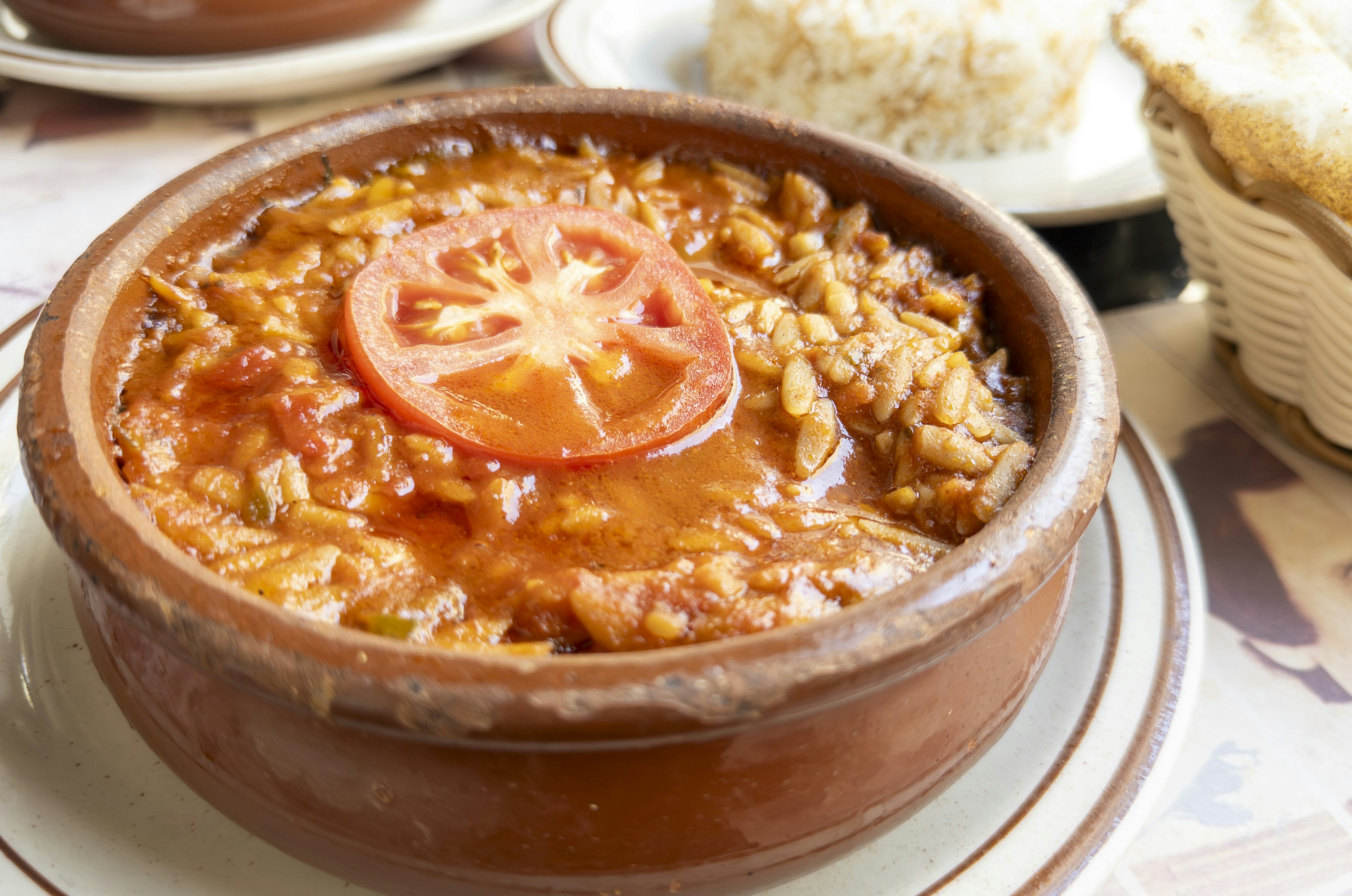 Guiso de tomate y pollo servido en un plato de barro