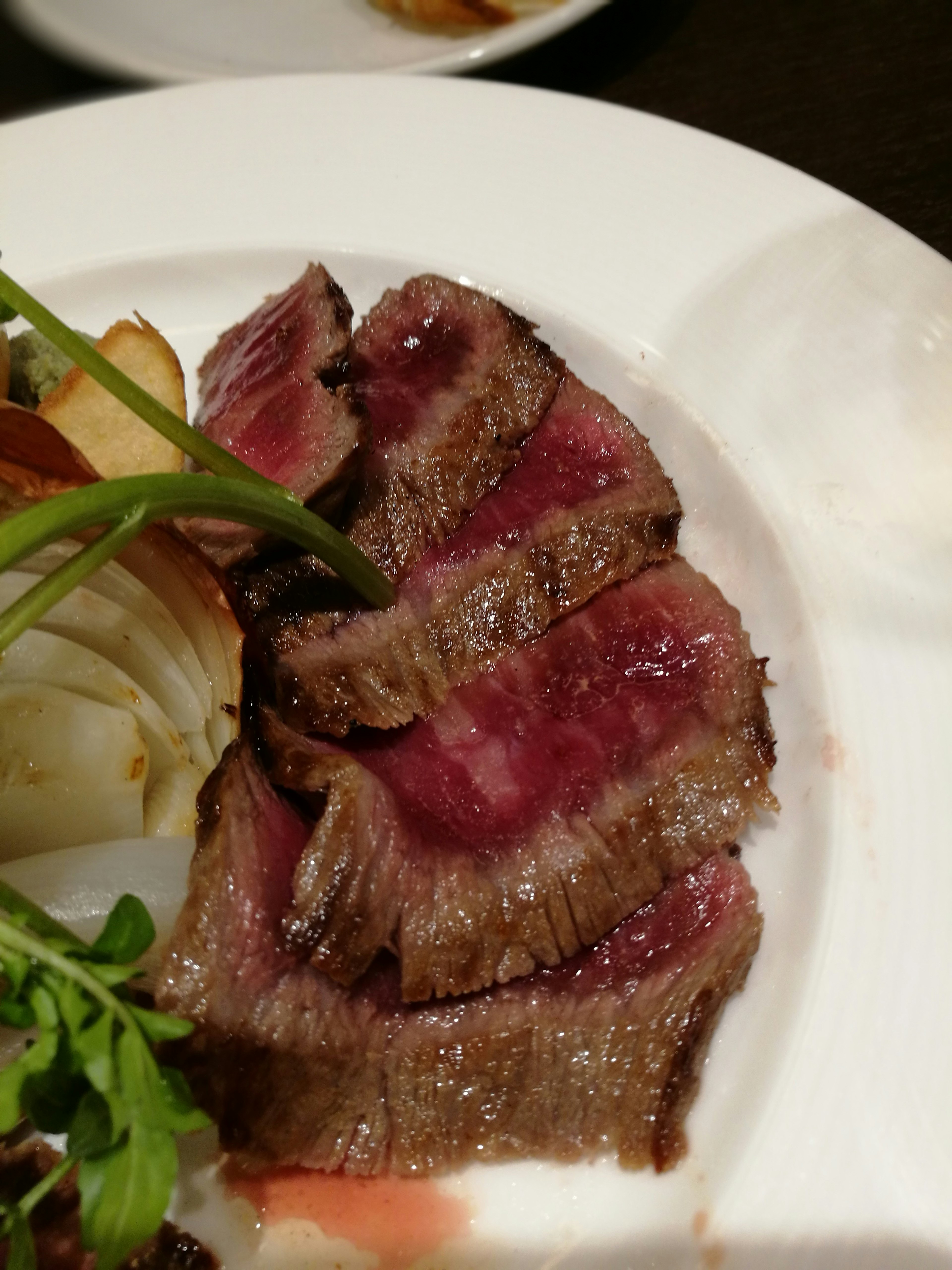 Plato de carne de res en rodajas con un bonito dorado y un interior jugoso