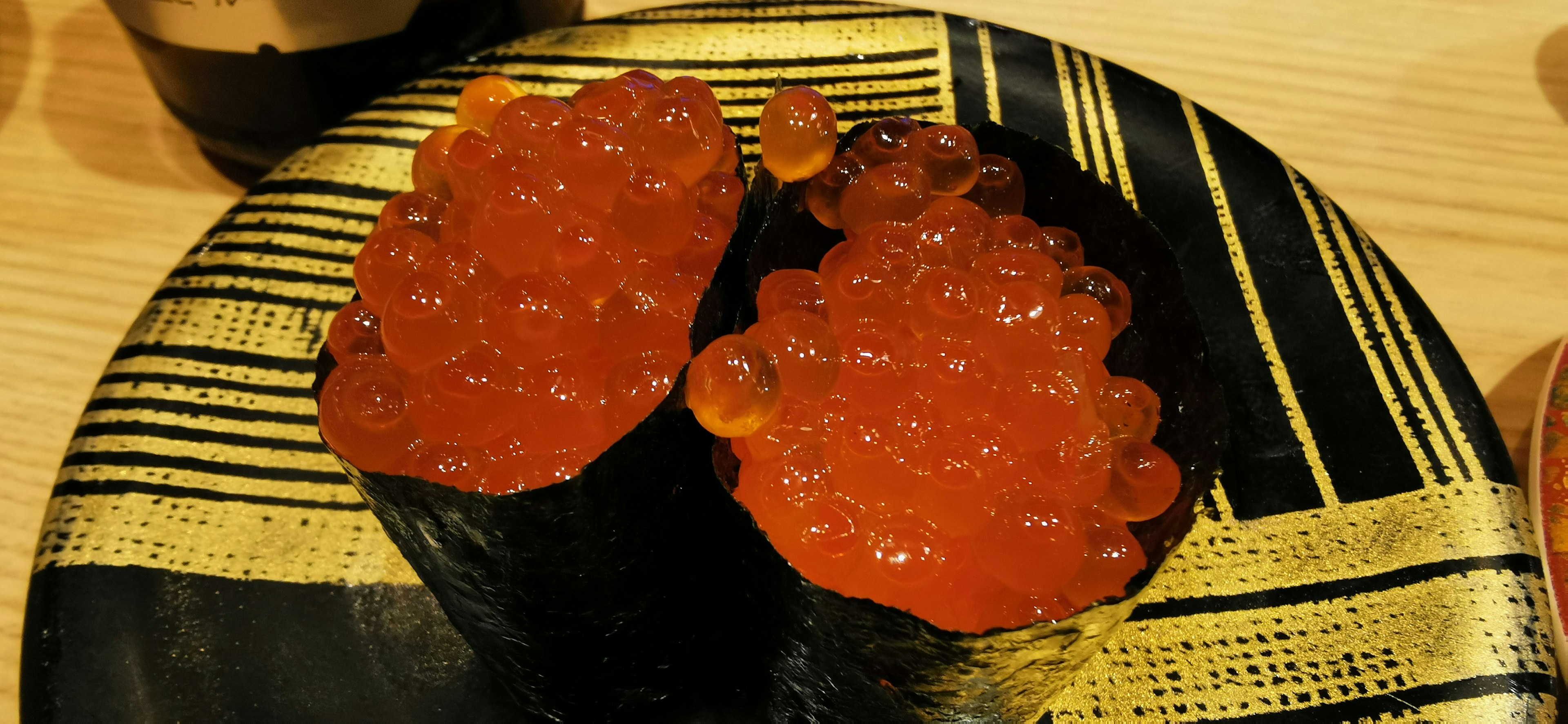 Dos piezas de sushi ikura en un plato negro