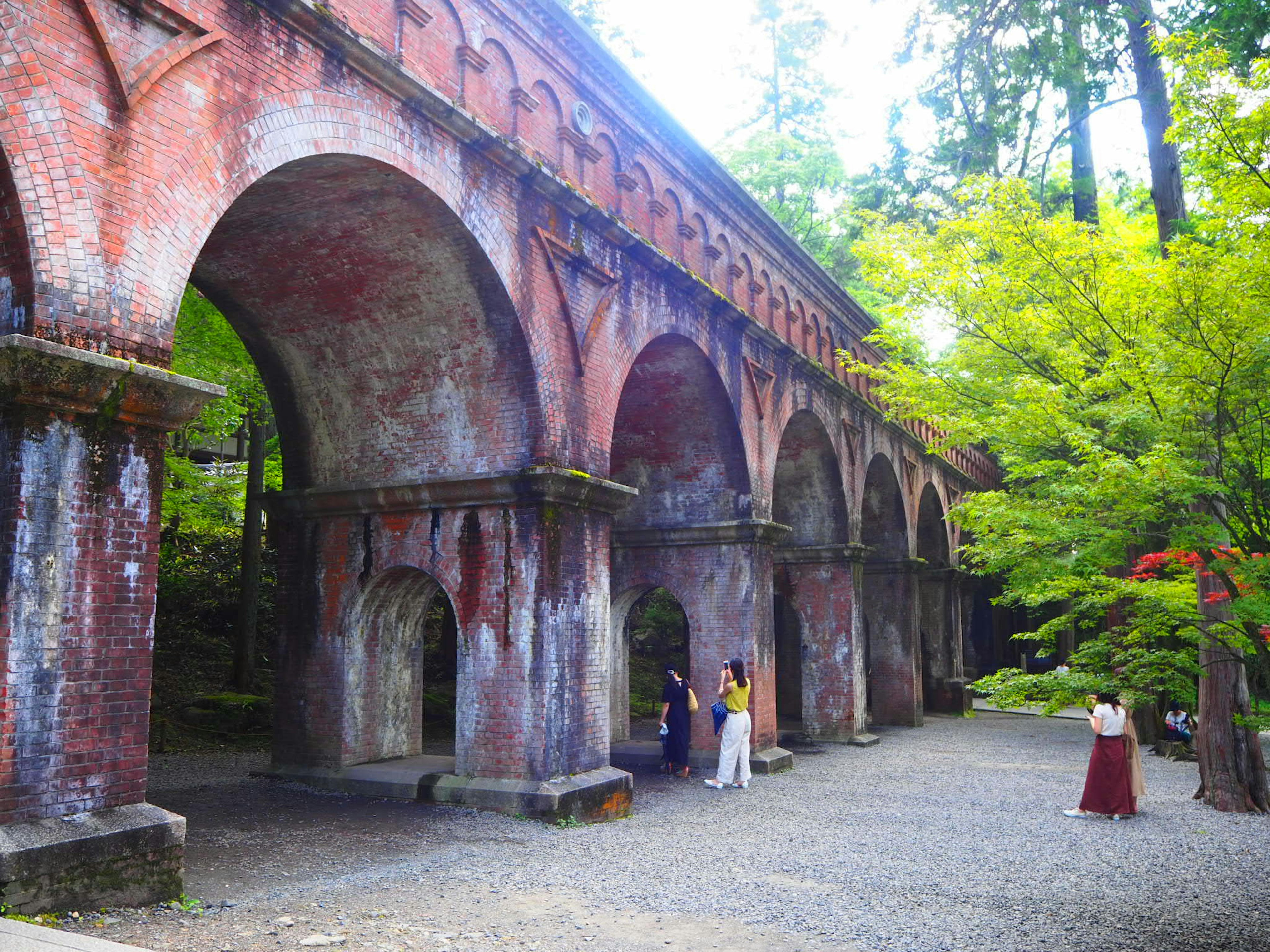 Pemandangan indah dari aqueduct tua dengan lengkungan merah dikelilingi oleh vegetasi