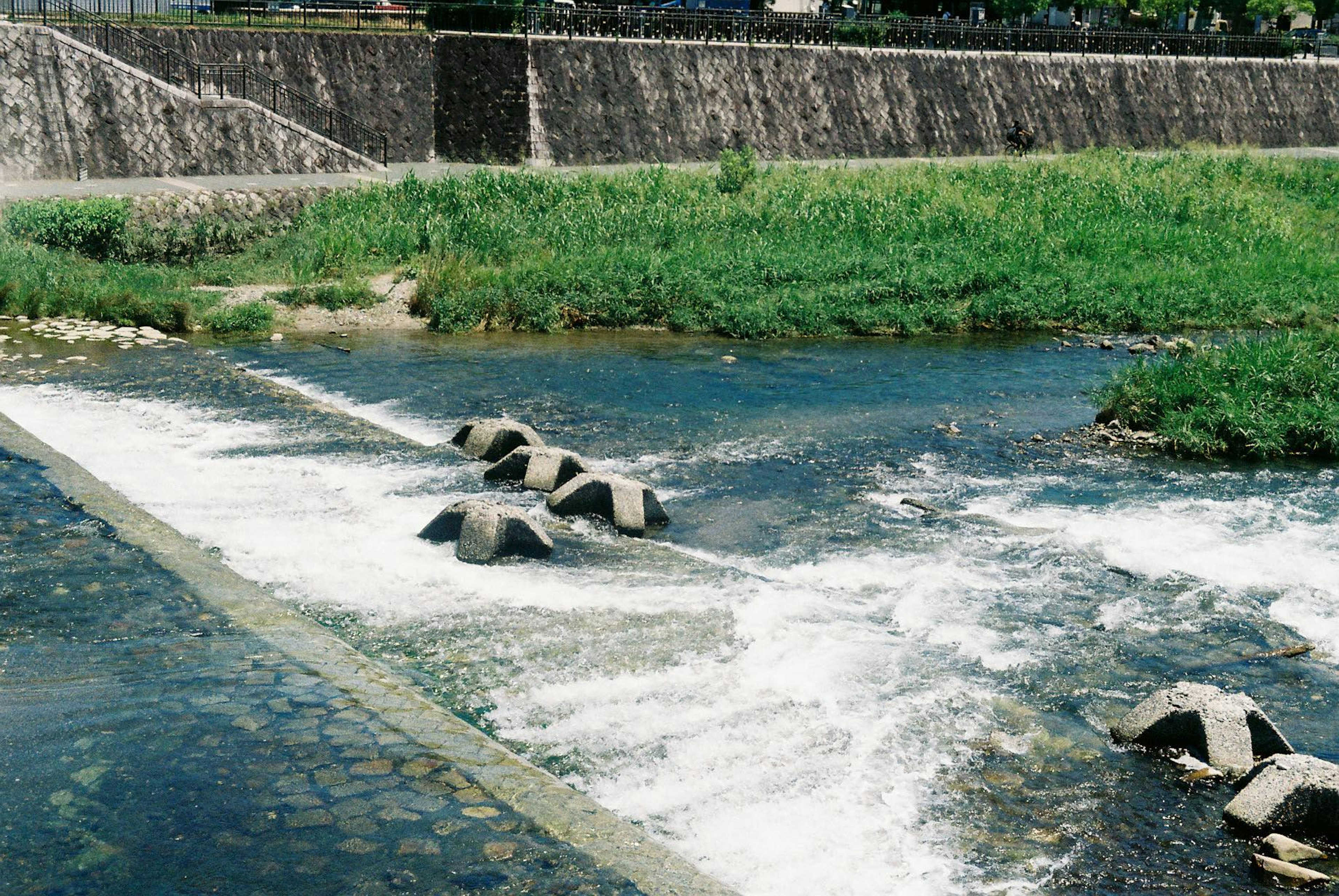 水流が流れる石の構造物と緑の草地