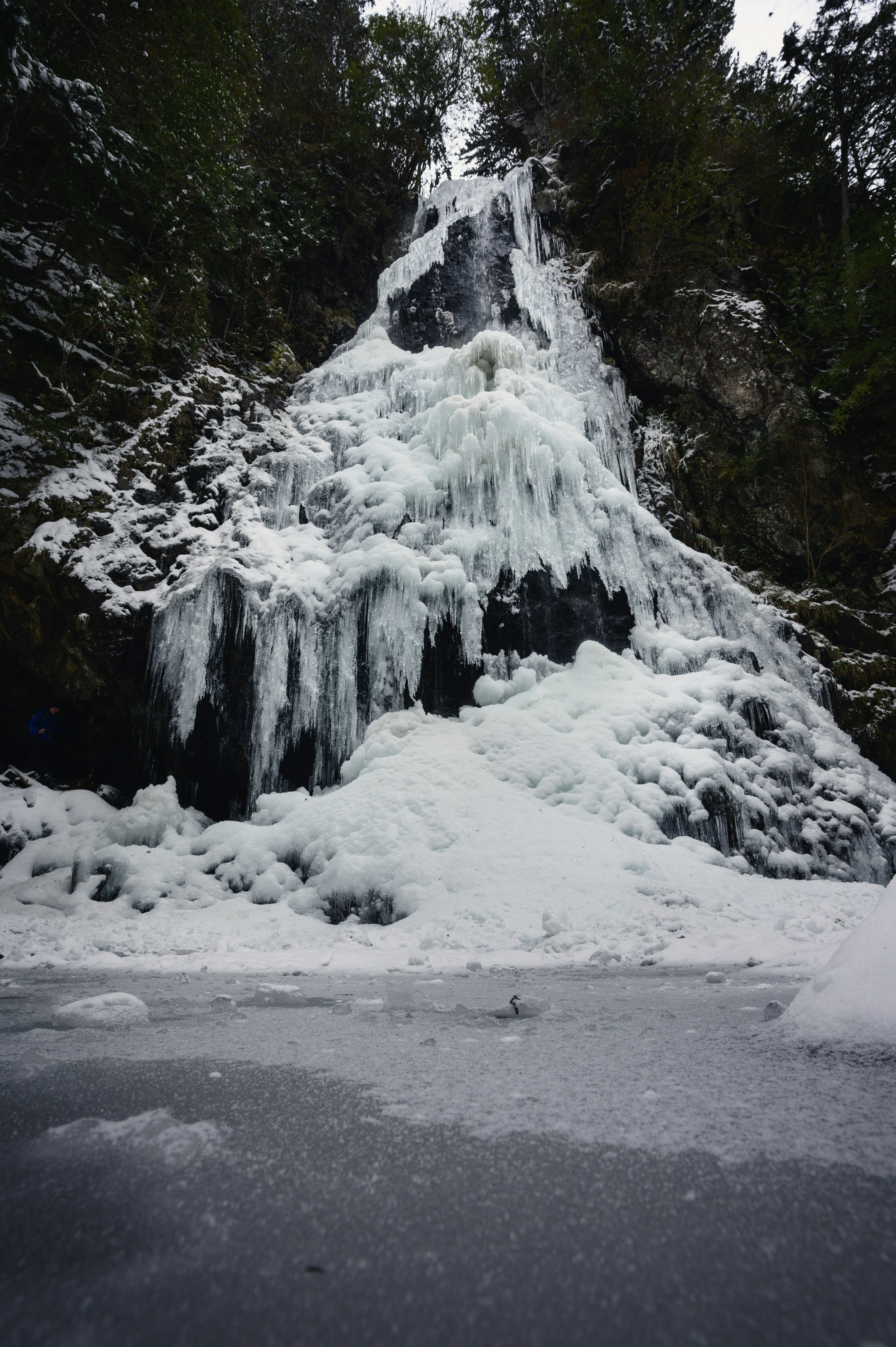 Cascata ghiacciata circondata da neve e ghiaccio