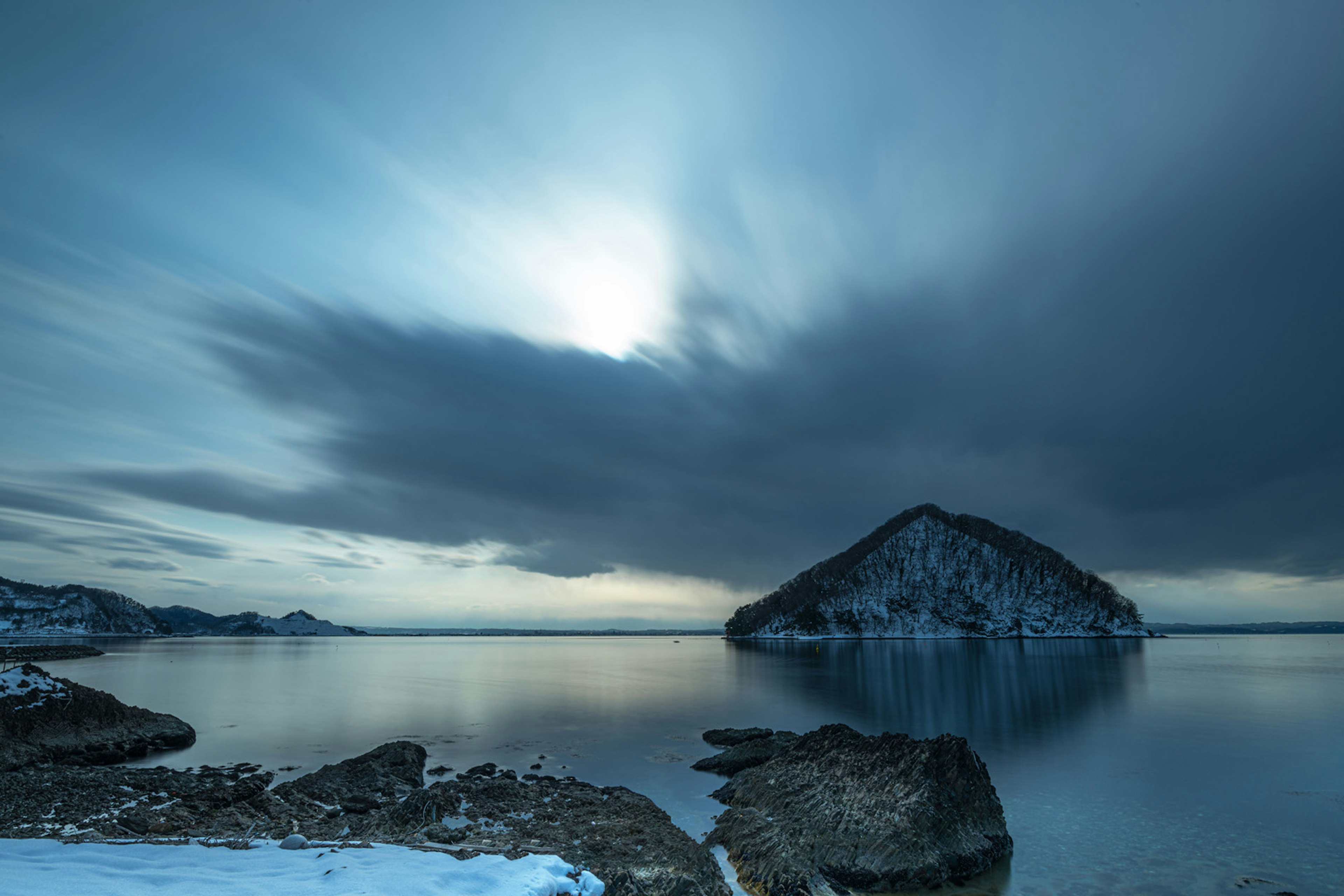 Winterlandschaft mit einer schneebedeckten Insel und ruhiger Wasseroberfläche