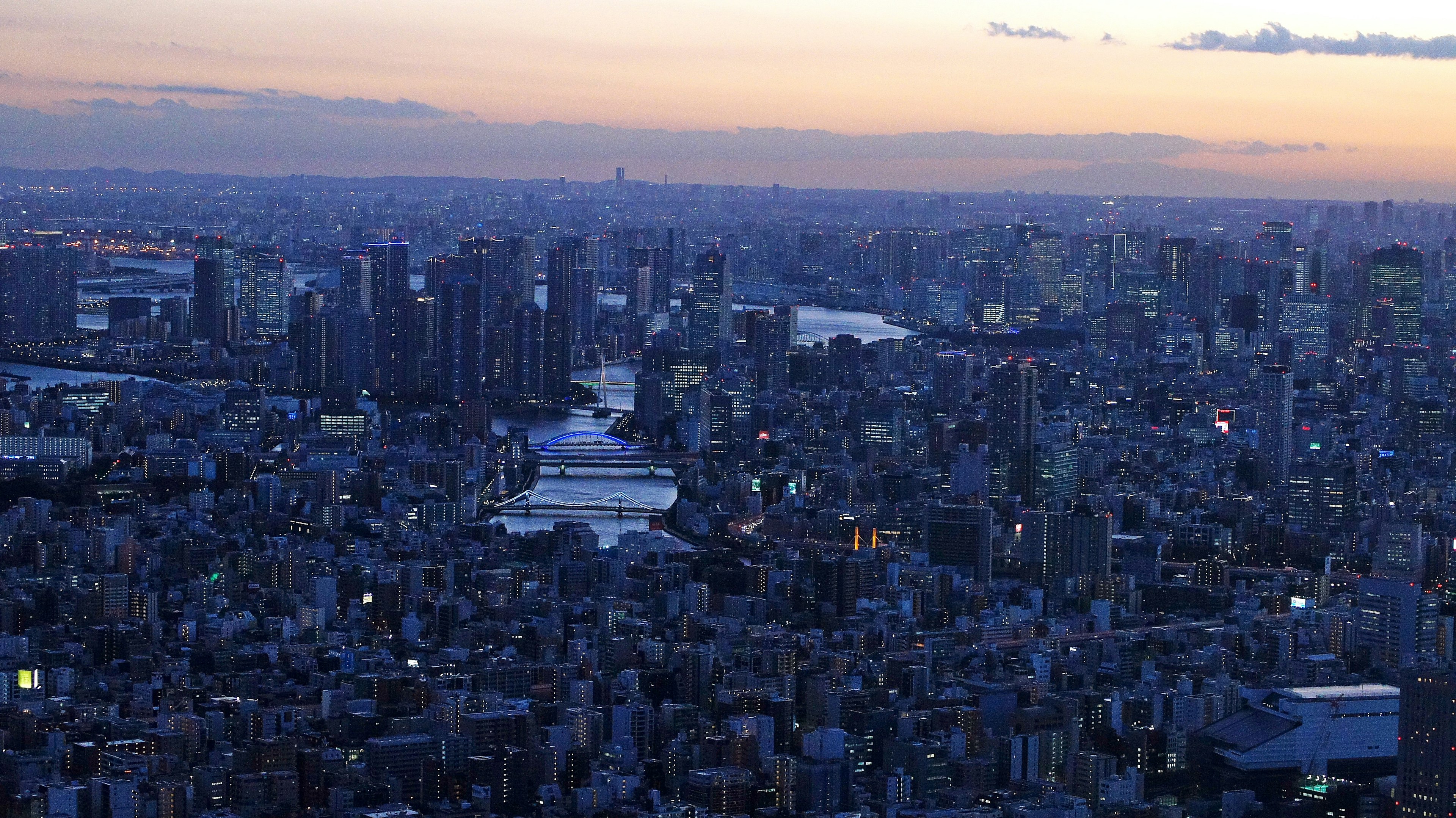 Pemandangan luas dari garis langit Tokyo dengan sungai dan lampu kota saat senja