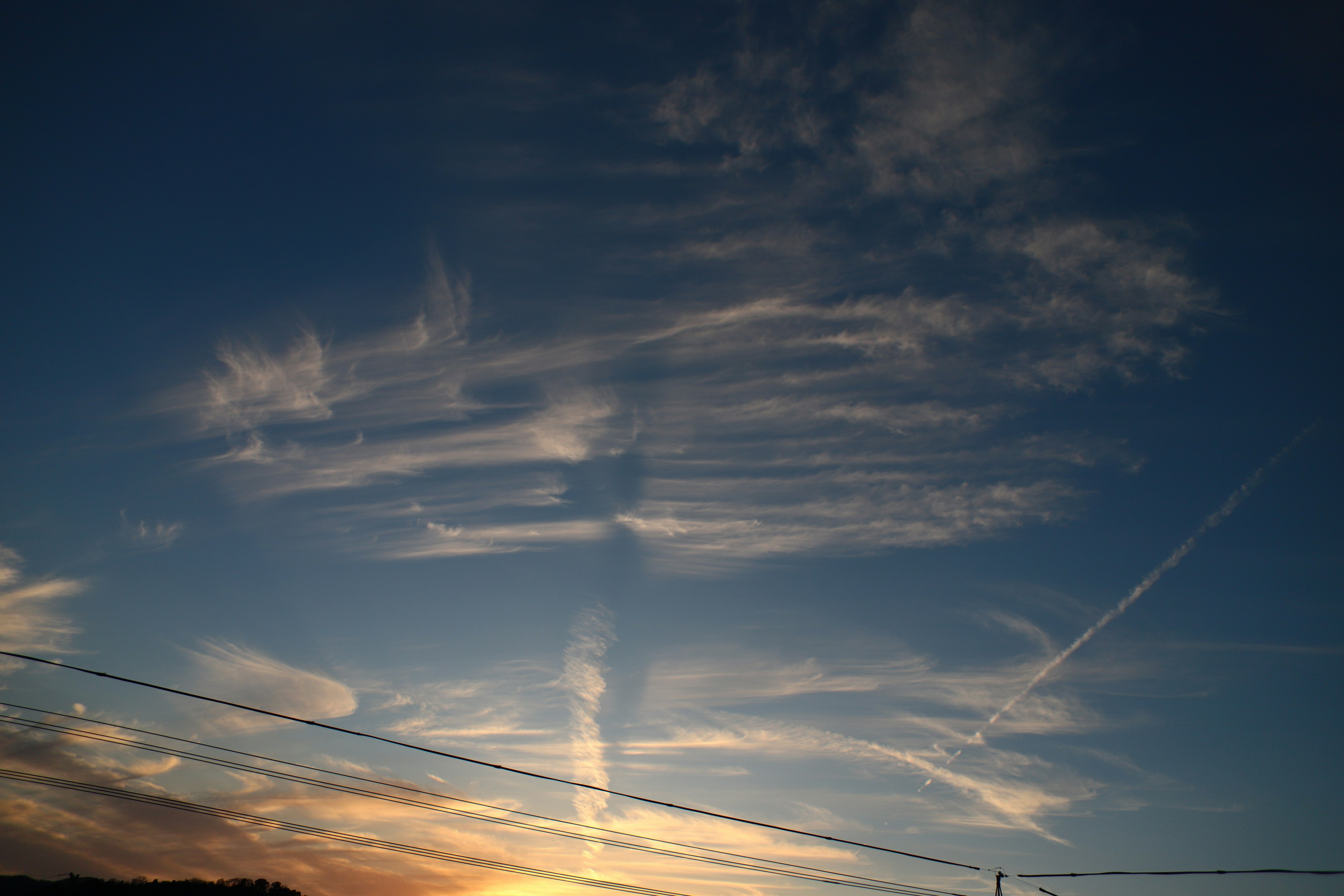 Motivi nuvolosi nel cielo al tramonto con scie di aerei