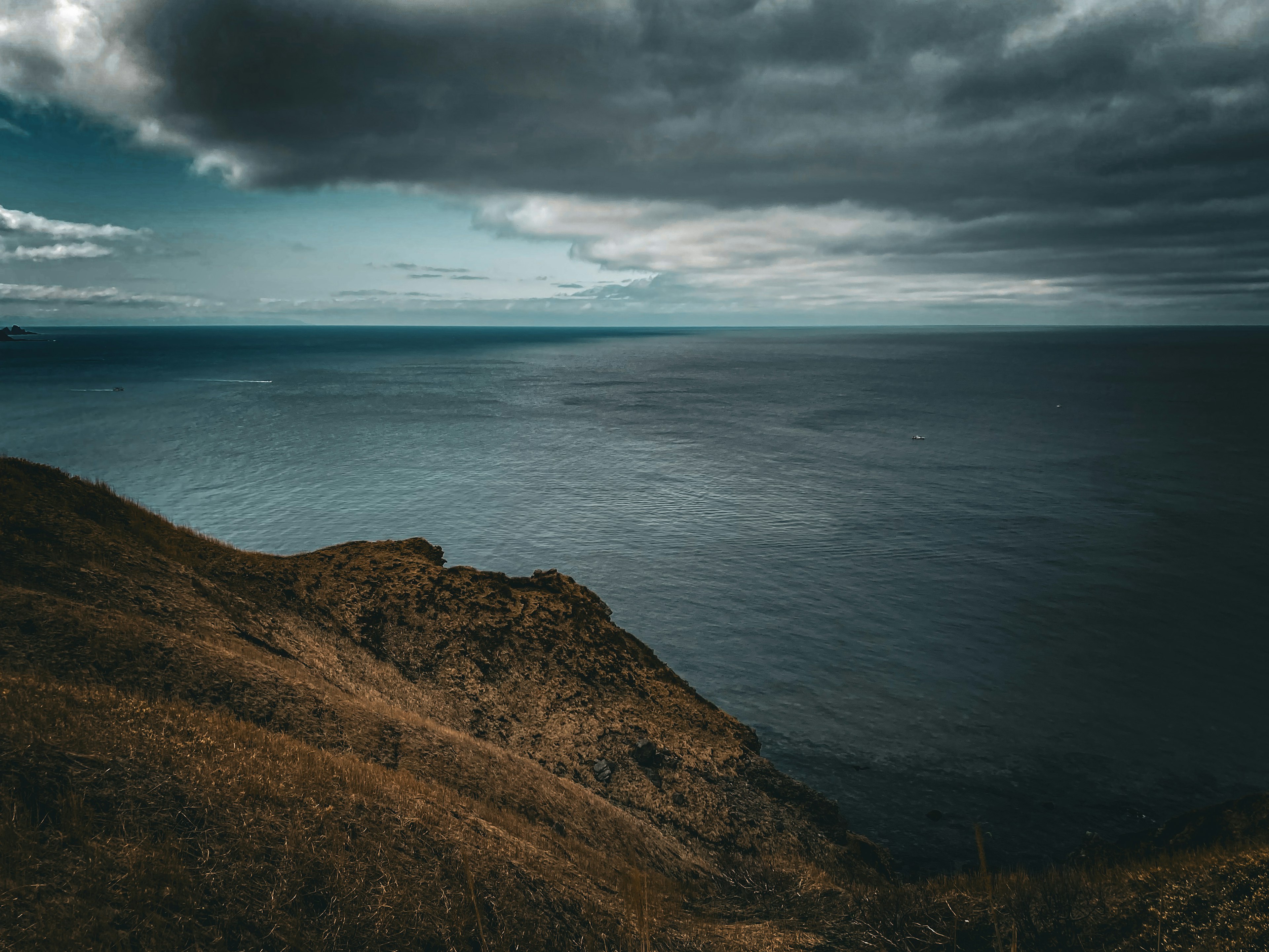 A rugged coastline with dark clouds over the ocean