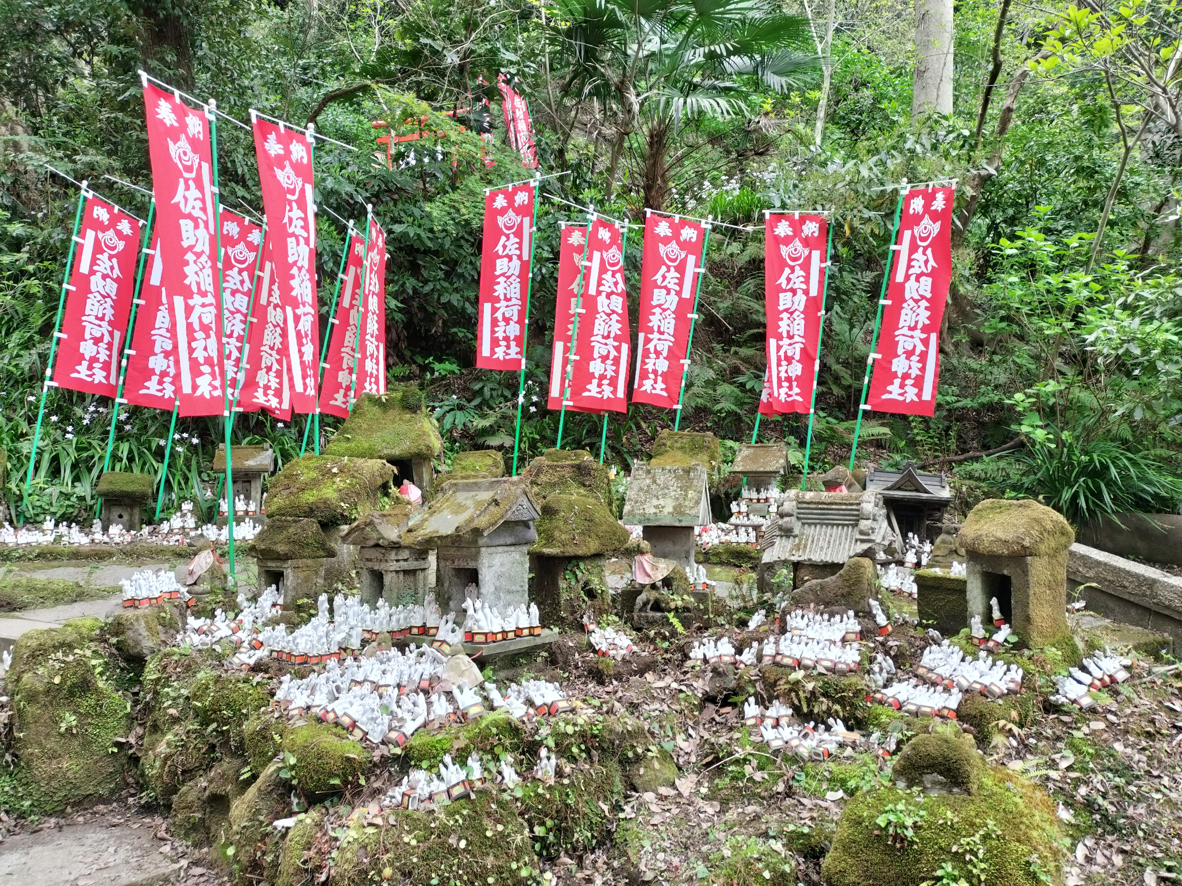 緑の森の中にある神社の小さな祭壇と赤い旗