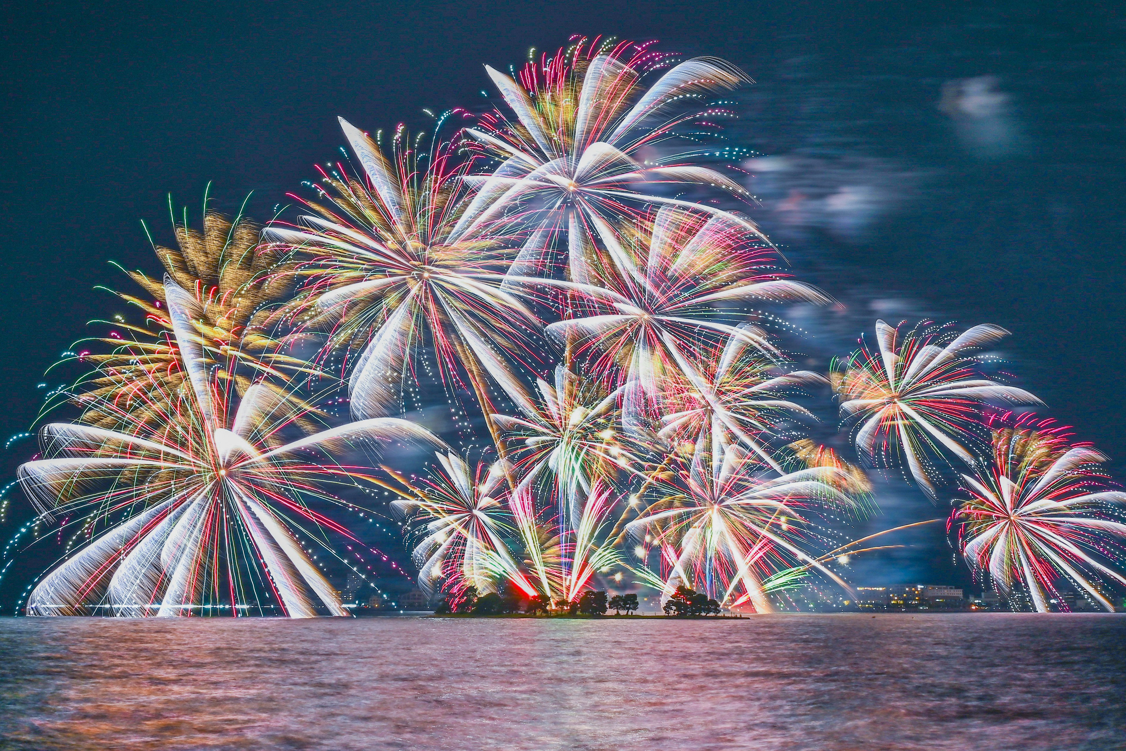 Fuochi d'artificio colorati che illuminano il cielo notturno riflessi sulla superficie dell'acqua