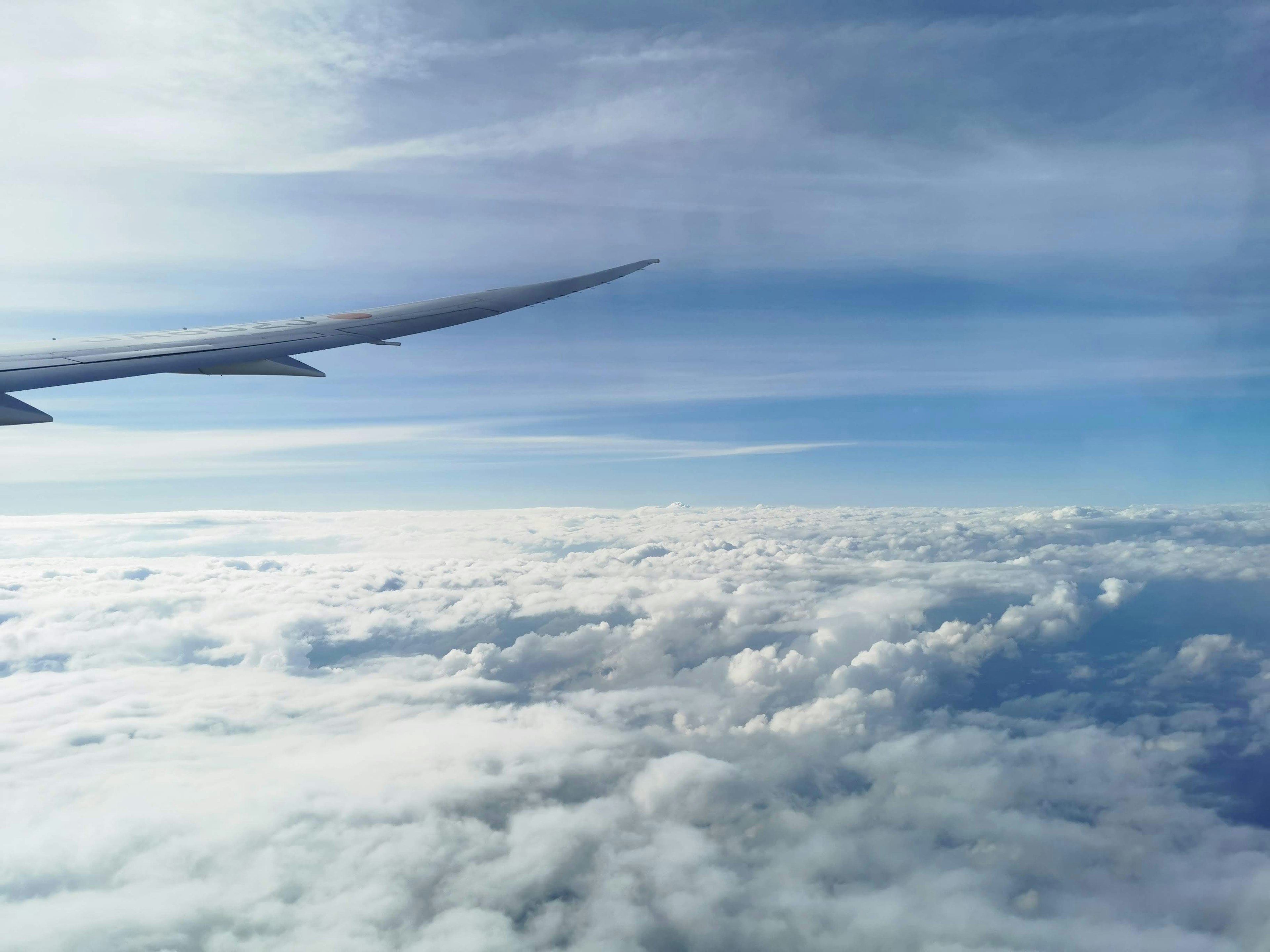 Airplane wing above white clouds and blue sky