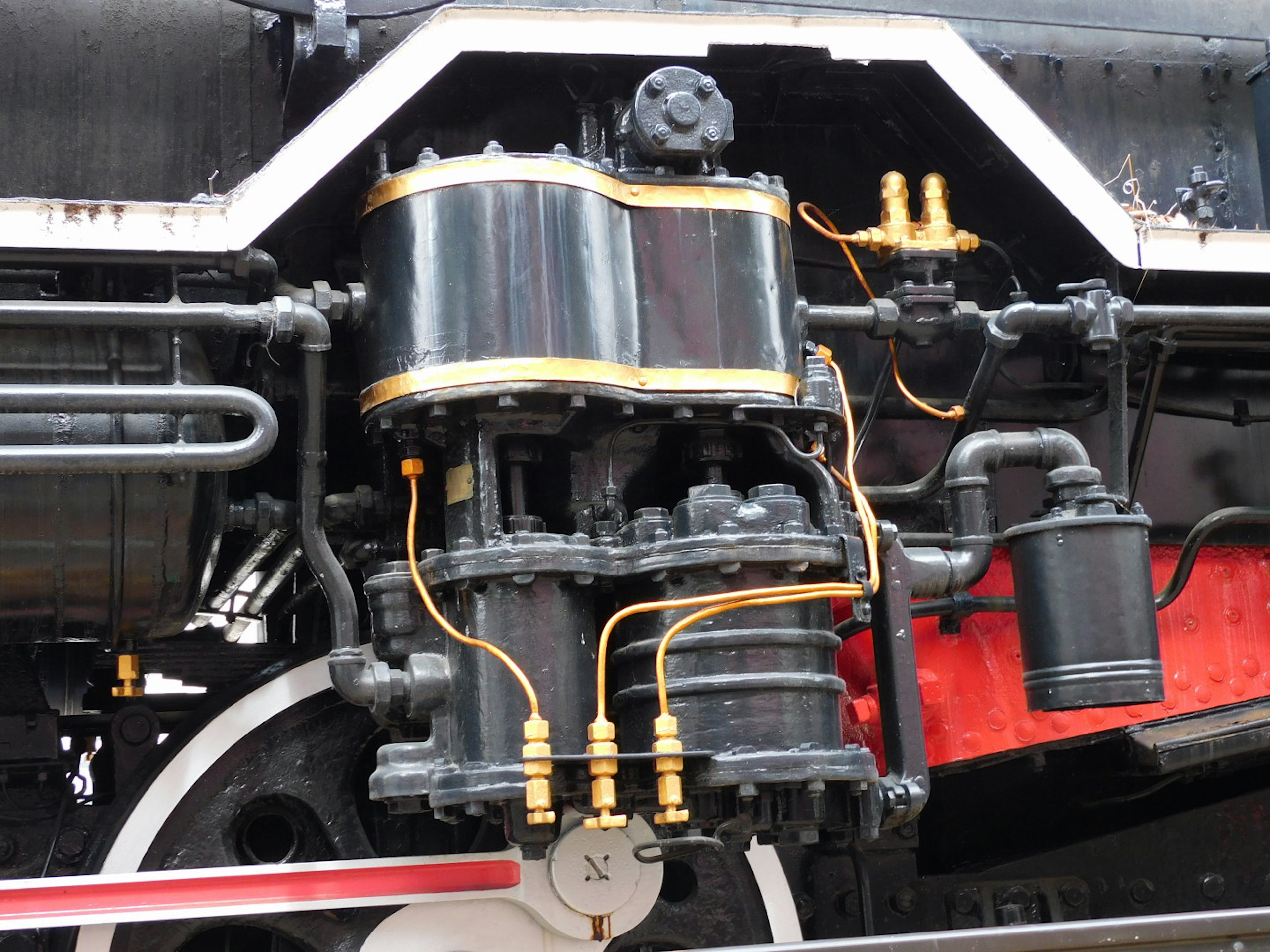 Vista dettagliata di un componente del motore di una locomotiva a vapore con metallo nero e tubazioni dorate