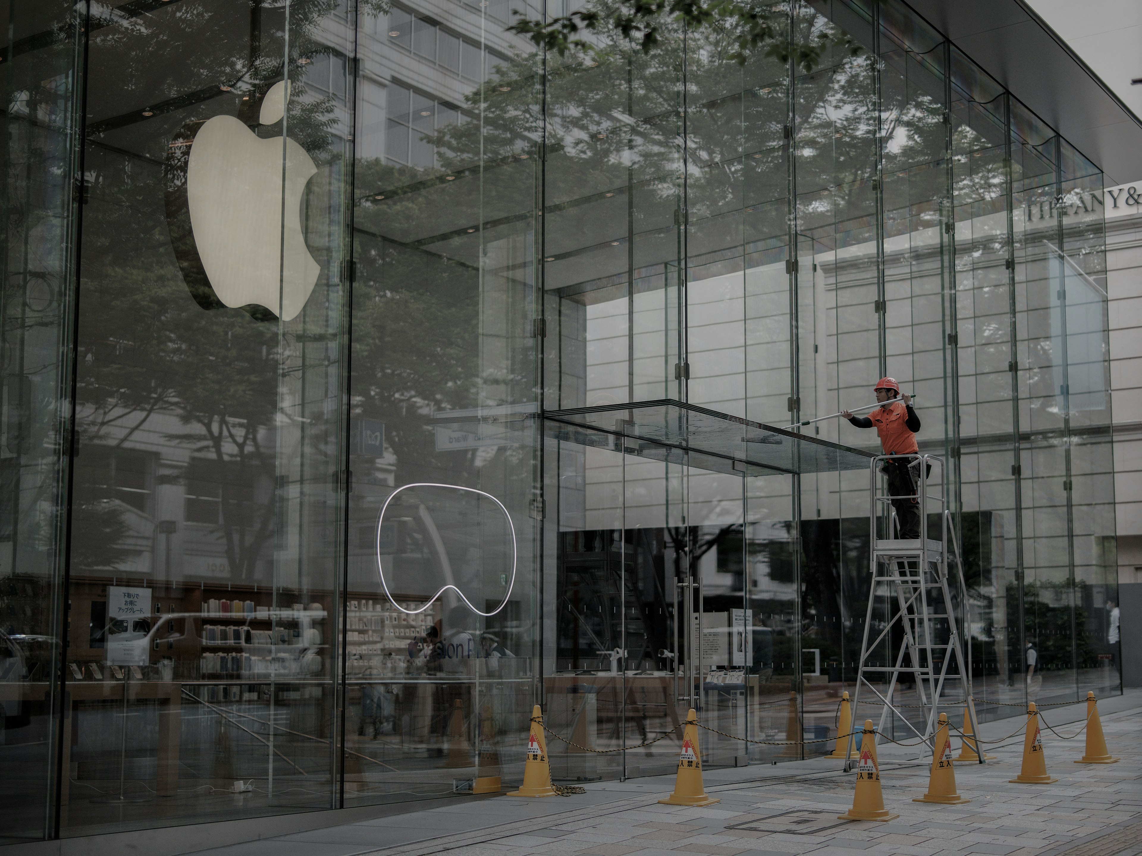 Arbeiter reinigt die Außenseite des Apple Stores mit einer Leiter