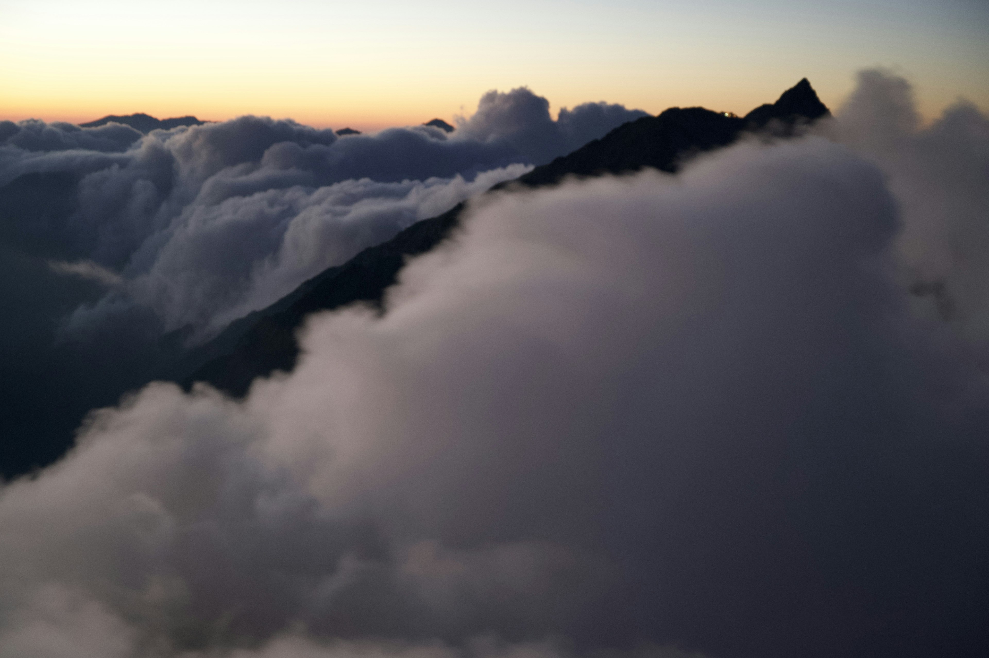 雲の合間から見える山のシルエットと夕焼けの空