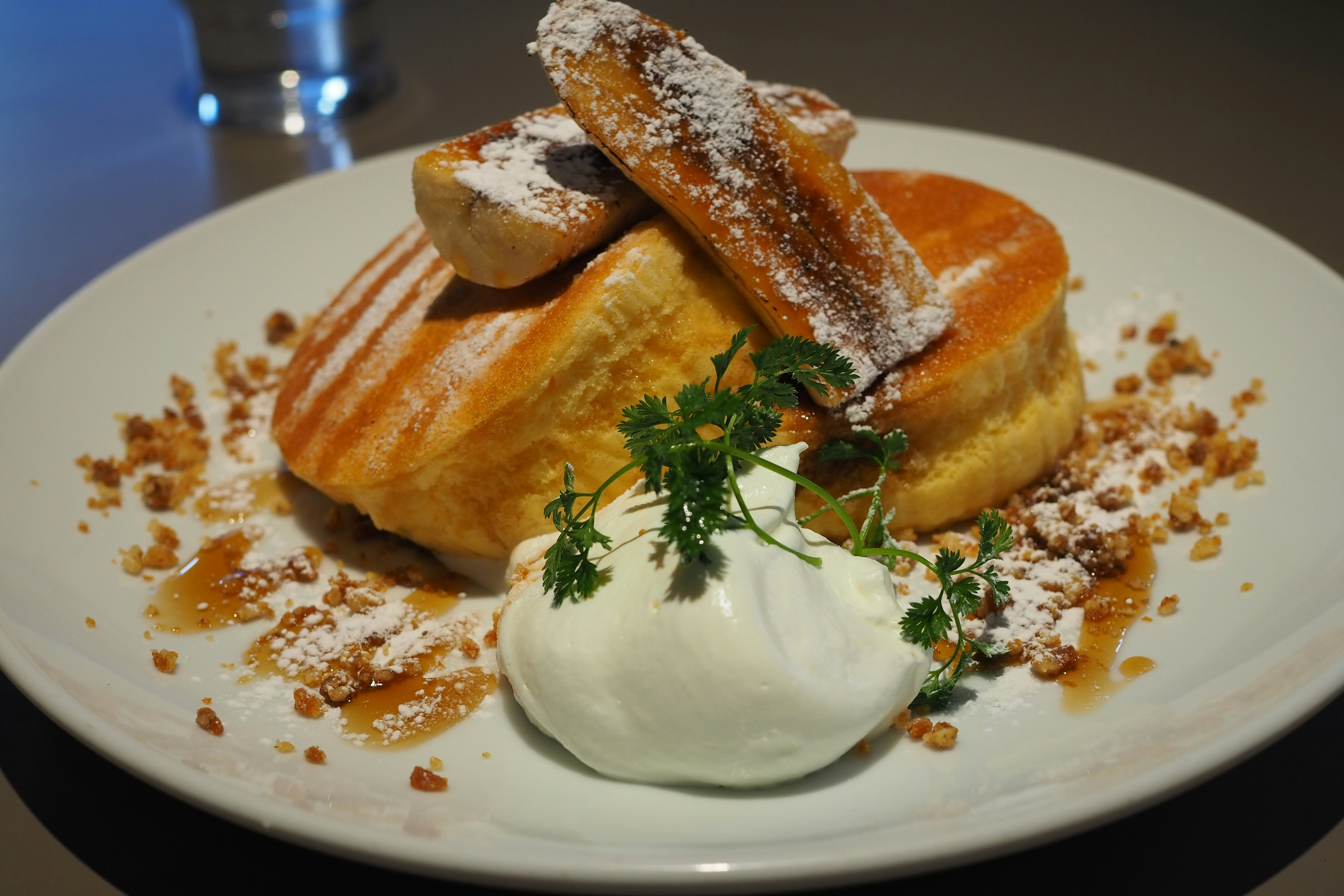 Fluffy pancakes topped with cream and fruit served on a plate