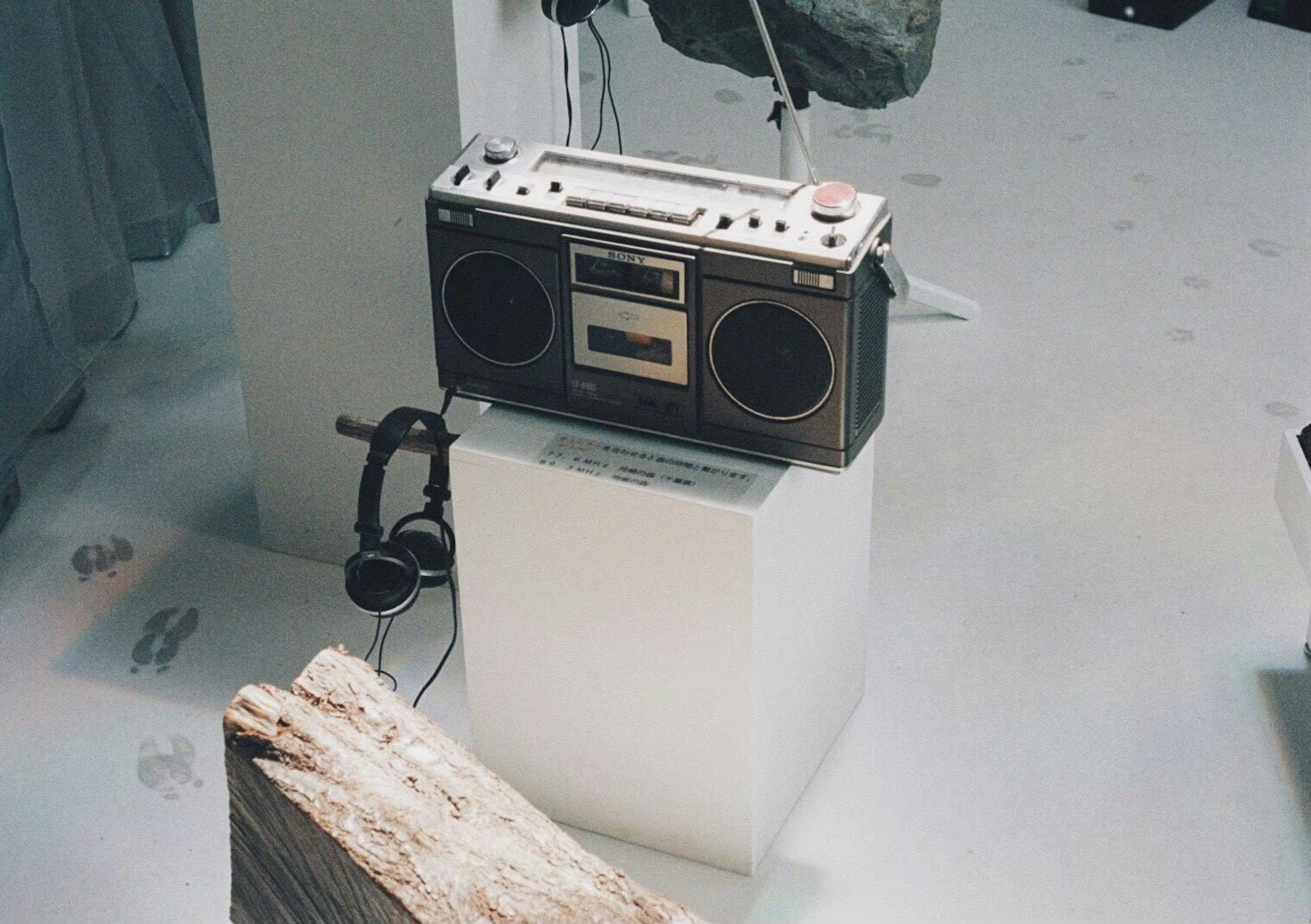 Retro boombox on a white pedestal with headphones nearby