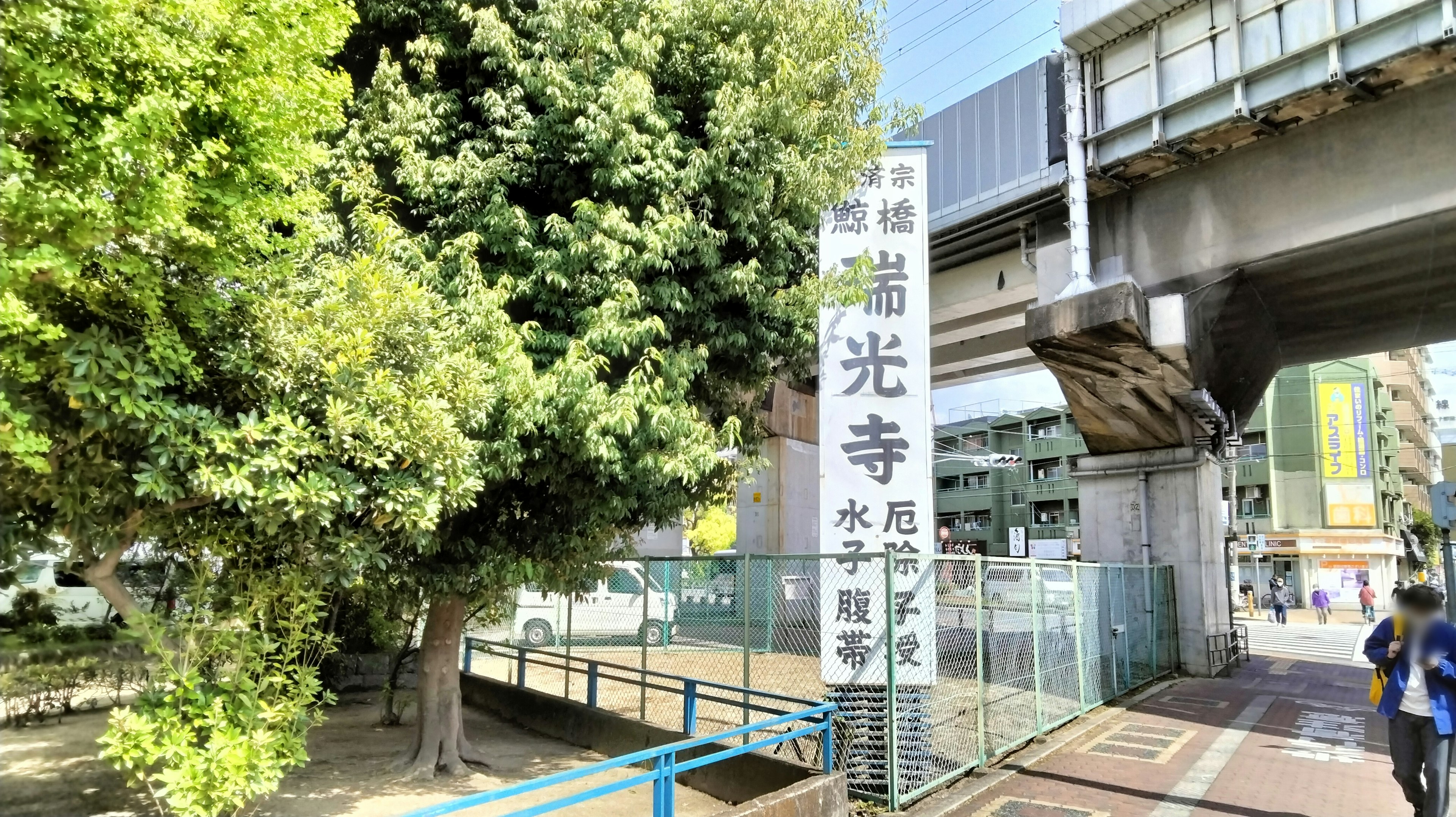 Pohon hijau rimbun dengan papan untuk Kōji Temple