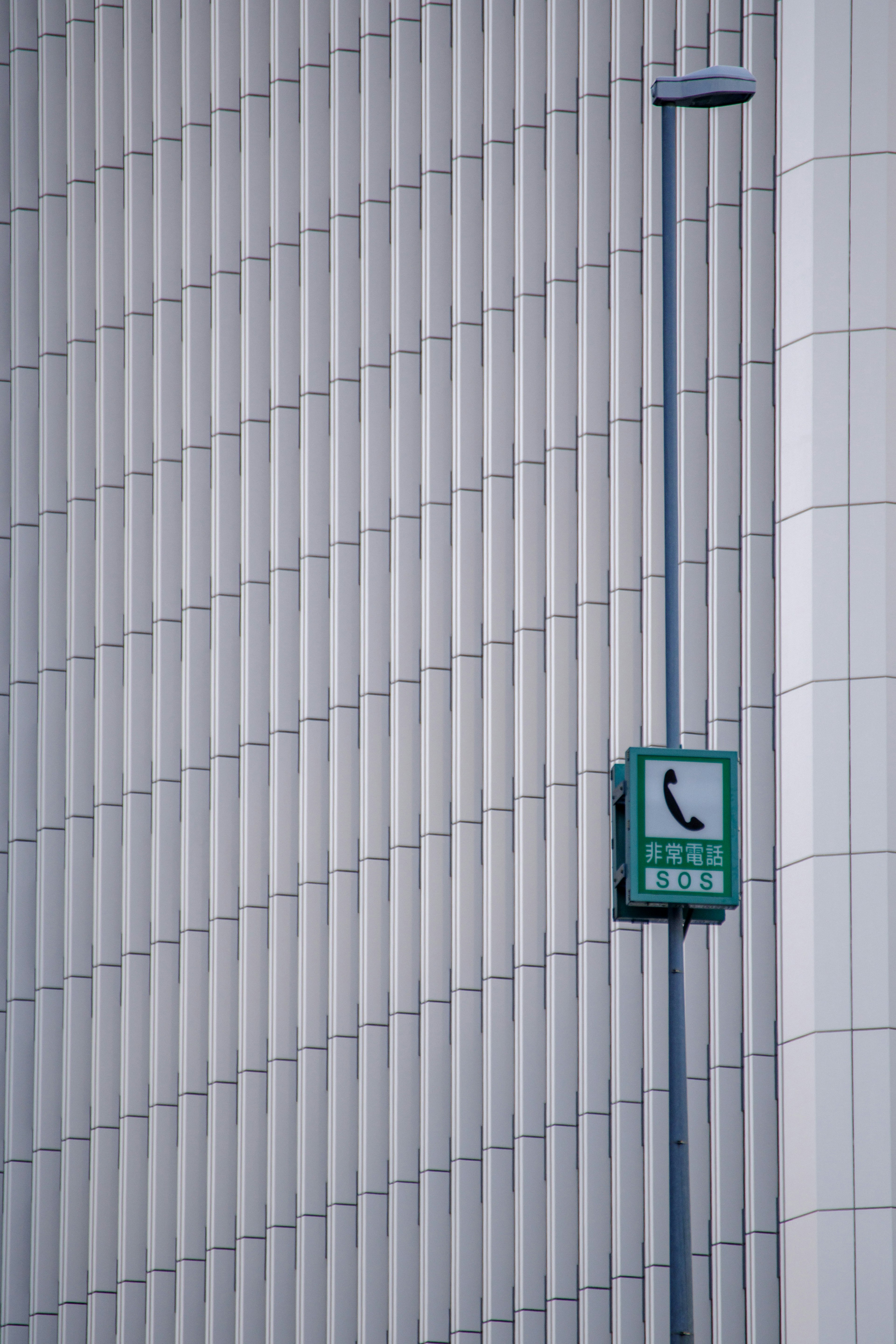 Cabine téléphonique publique verte fixée à un mur à rayures verticales blanches