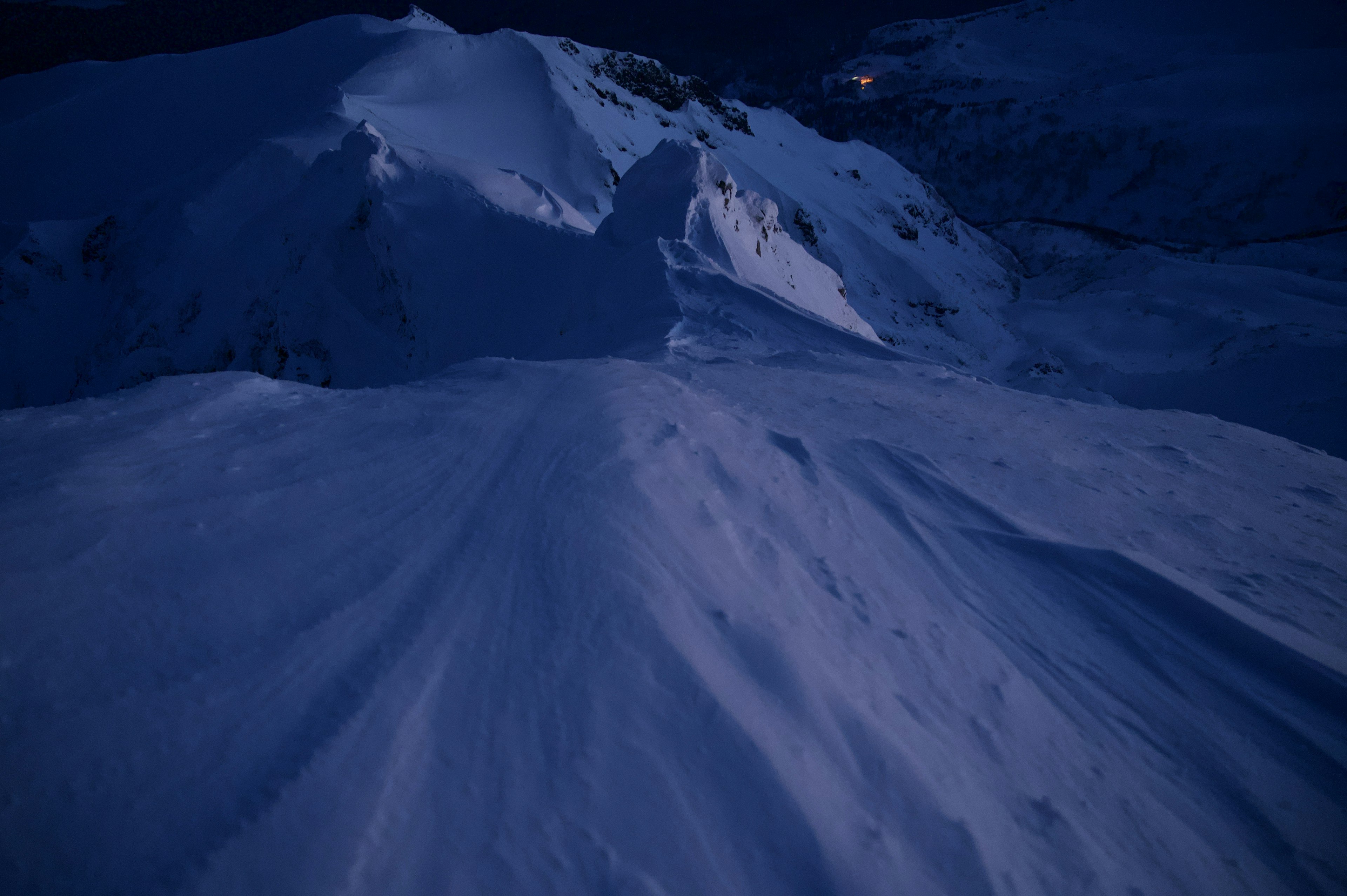 Vue nocturne d'une montagne enneigée avec une surface de neige lisse et un ciel sombre