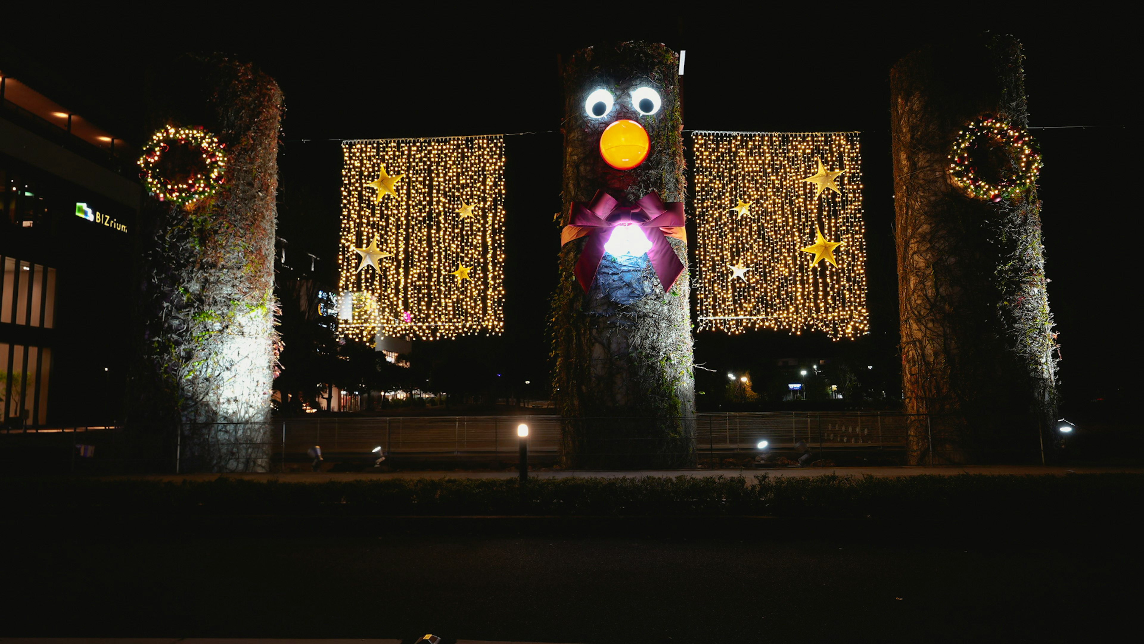 夜のイルミネーションを背景にした二つの装飾された石柱と中央に大きなキャラクターの飾り