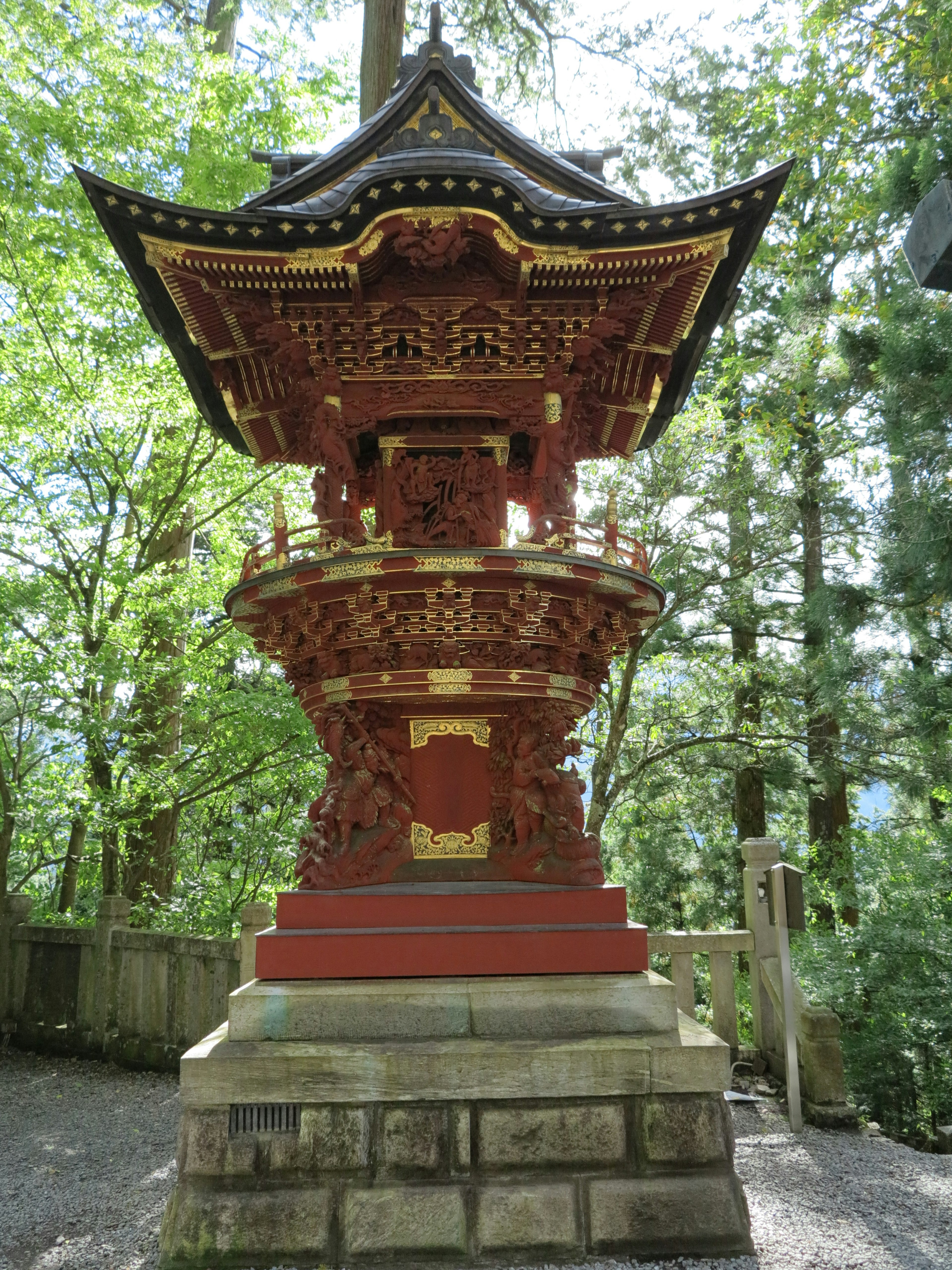 赤い寺院の塔が緑の木々に囲まれて立っている