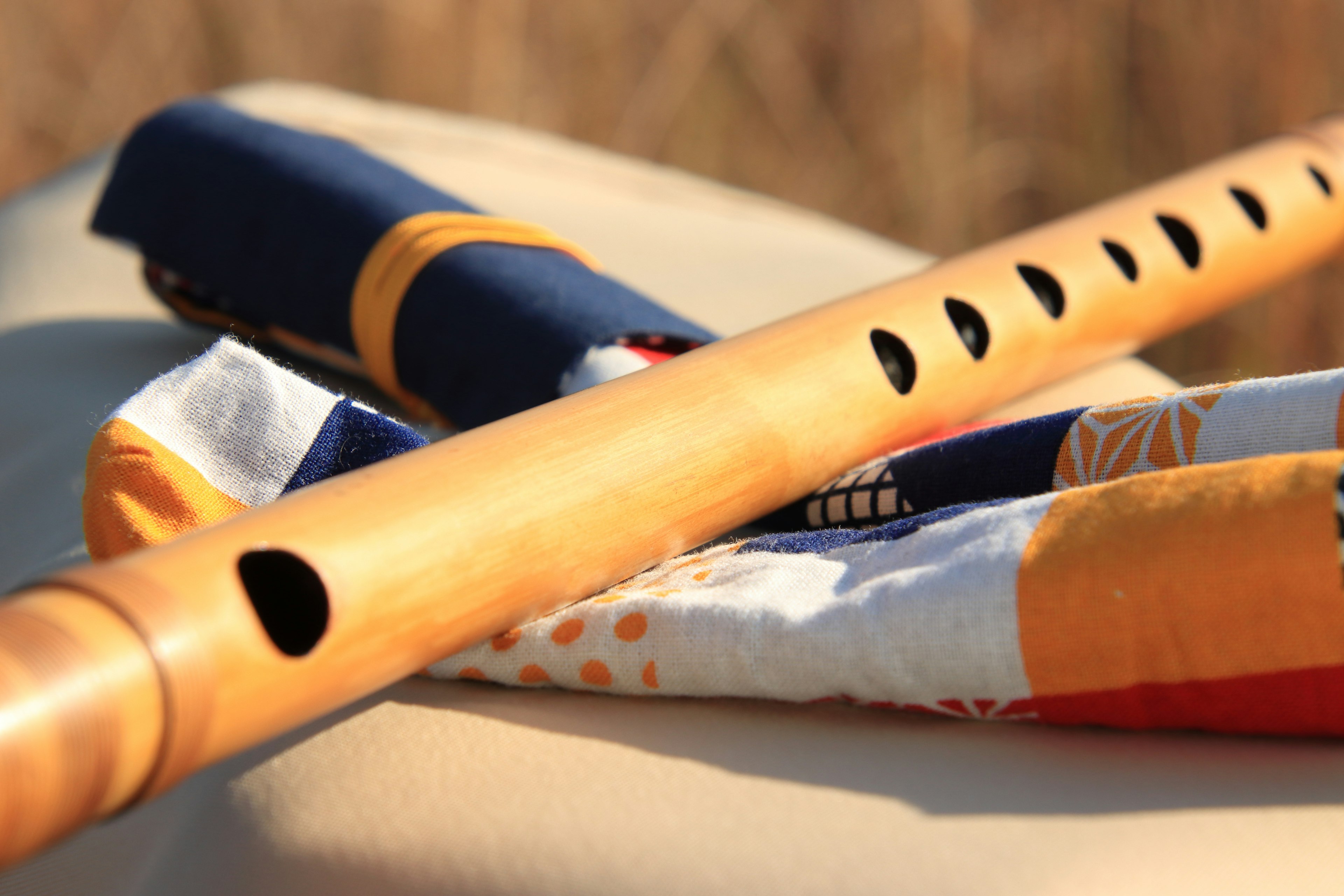 Image of wooden flute and colorful fabric laid out