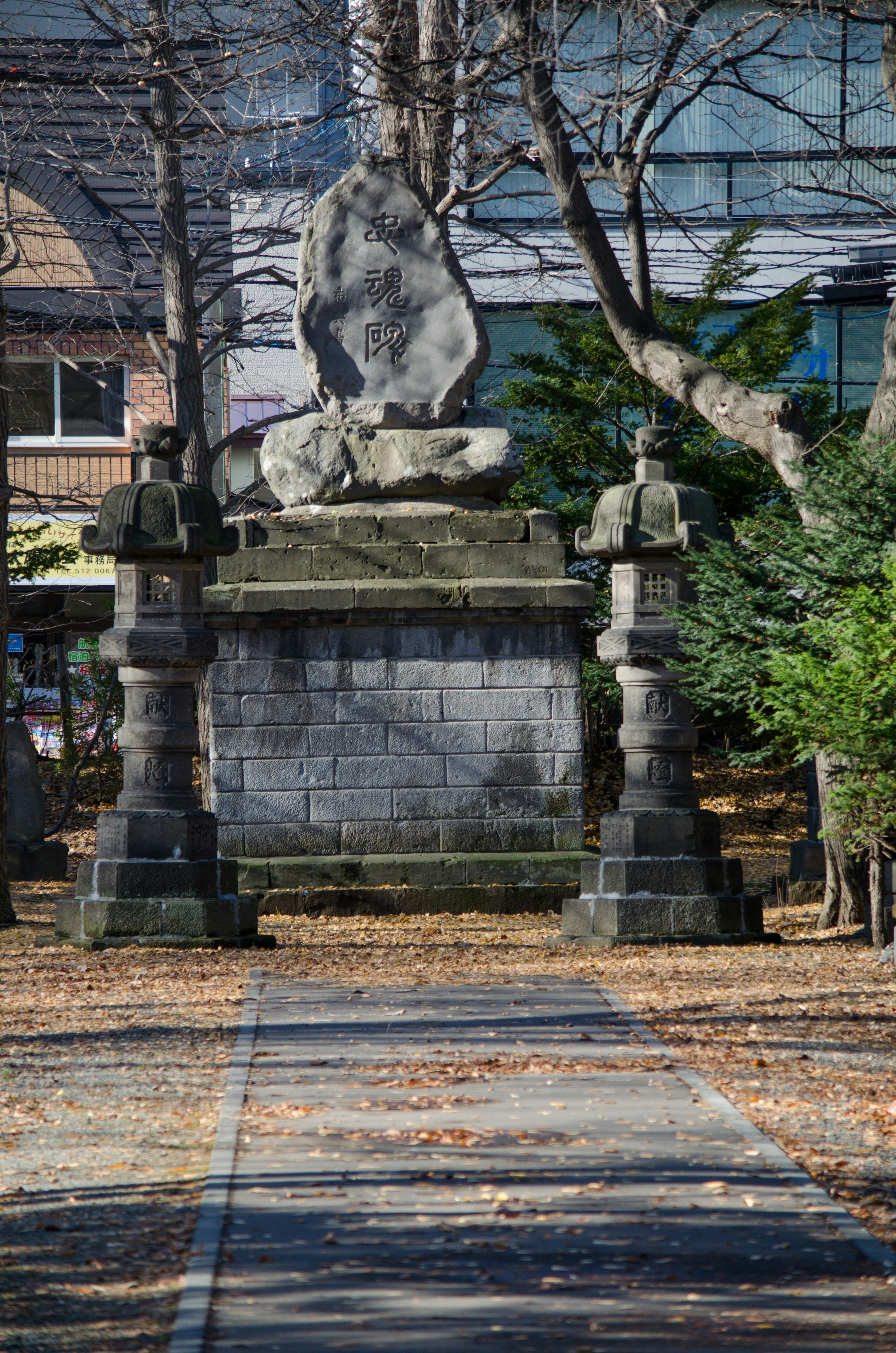 Chemin avec un monument en pierre et des lanternes dans un parc