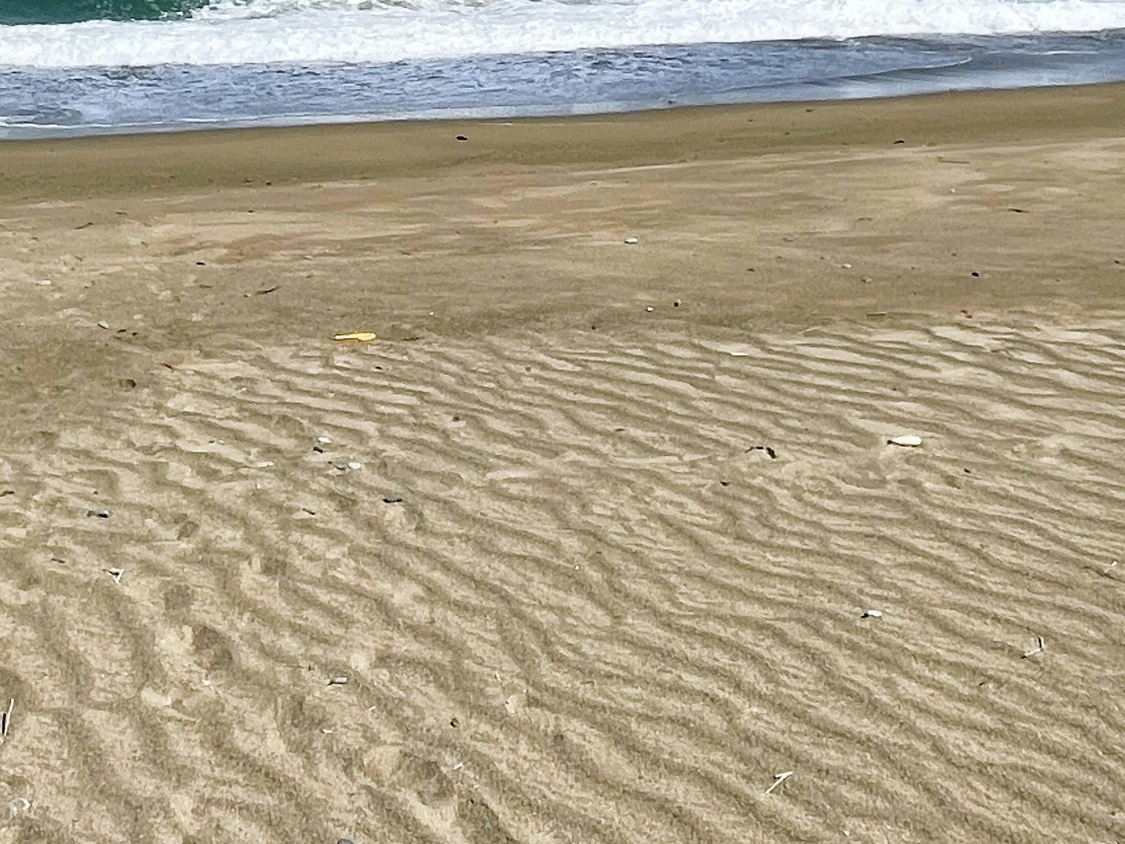 Wellen brechen an einem Sandstrand mit Wellenmuster