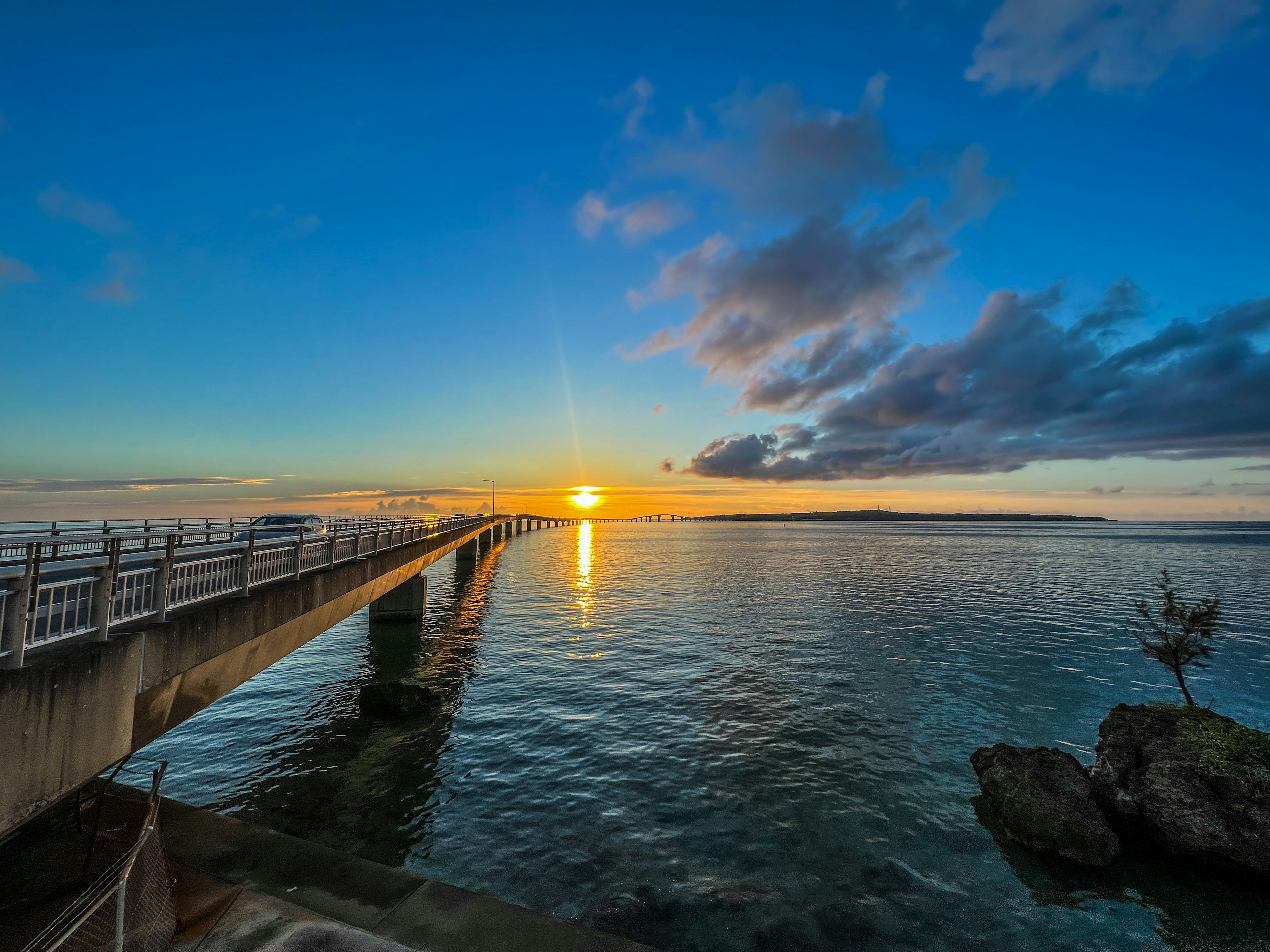 Muelle largo que se extiende hacia el mar con un atardecer y agua tranquila