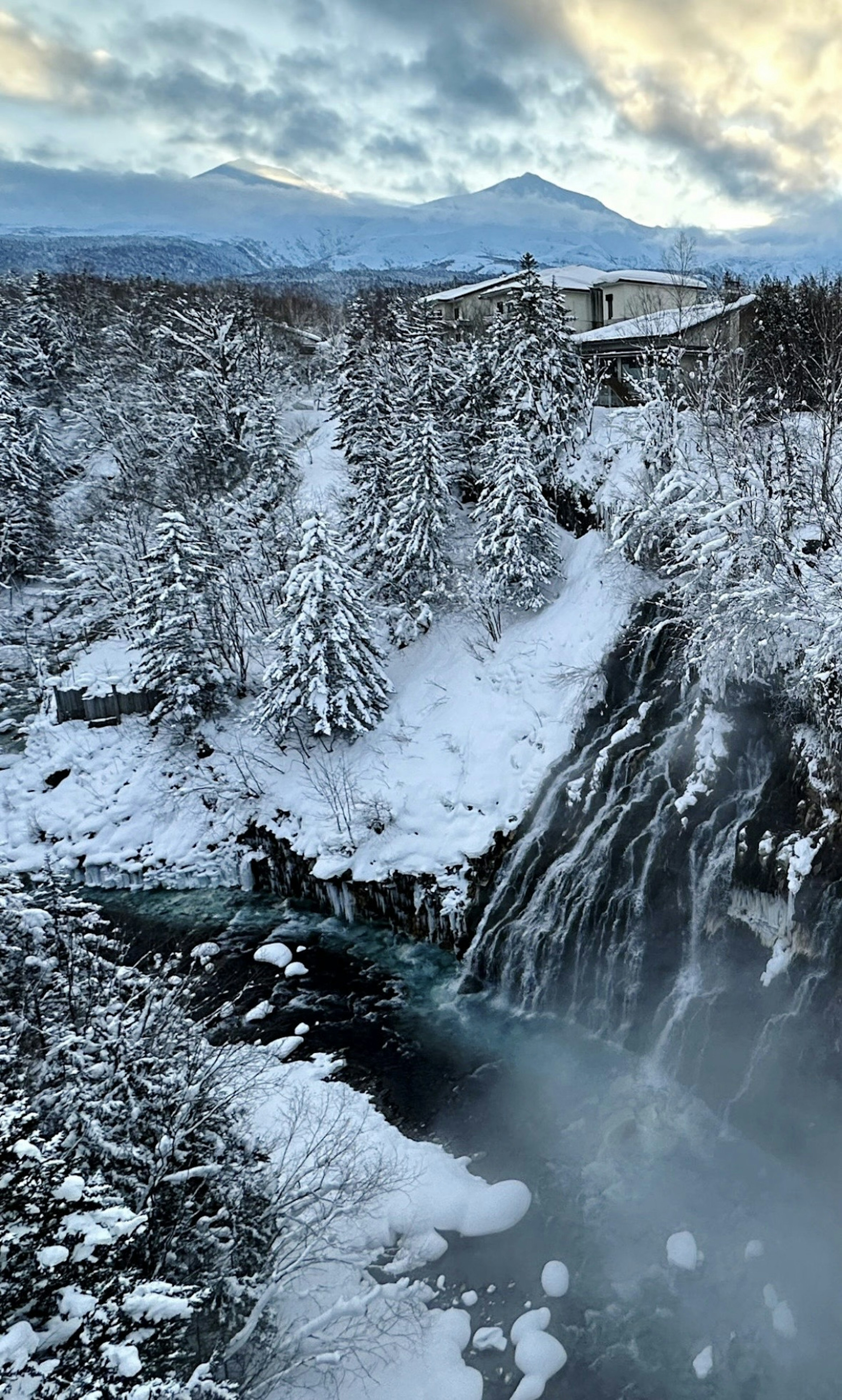 Winter landscape featuring a snow-covered waterfall and mountains