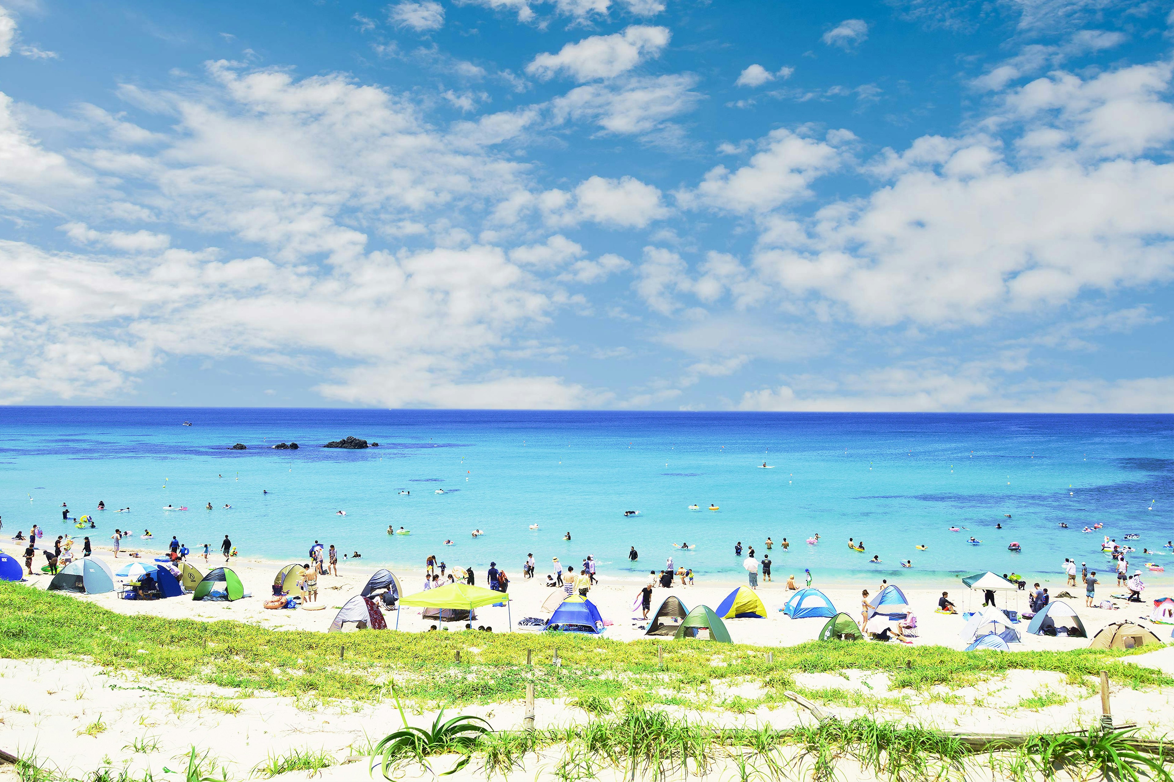 青い海と青空のビーチに人々が集まる風景