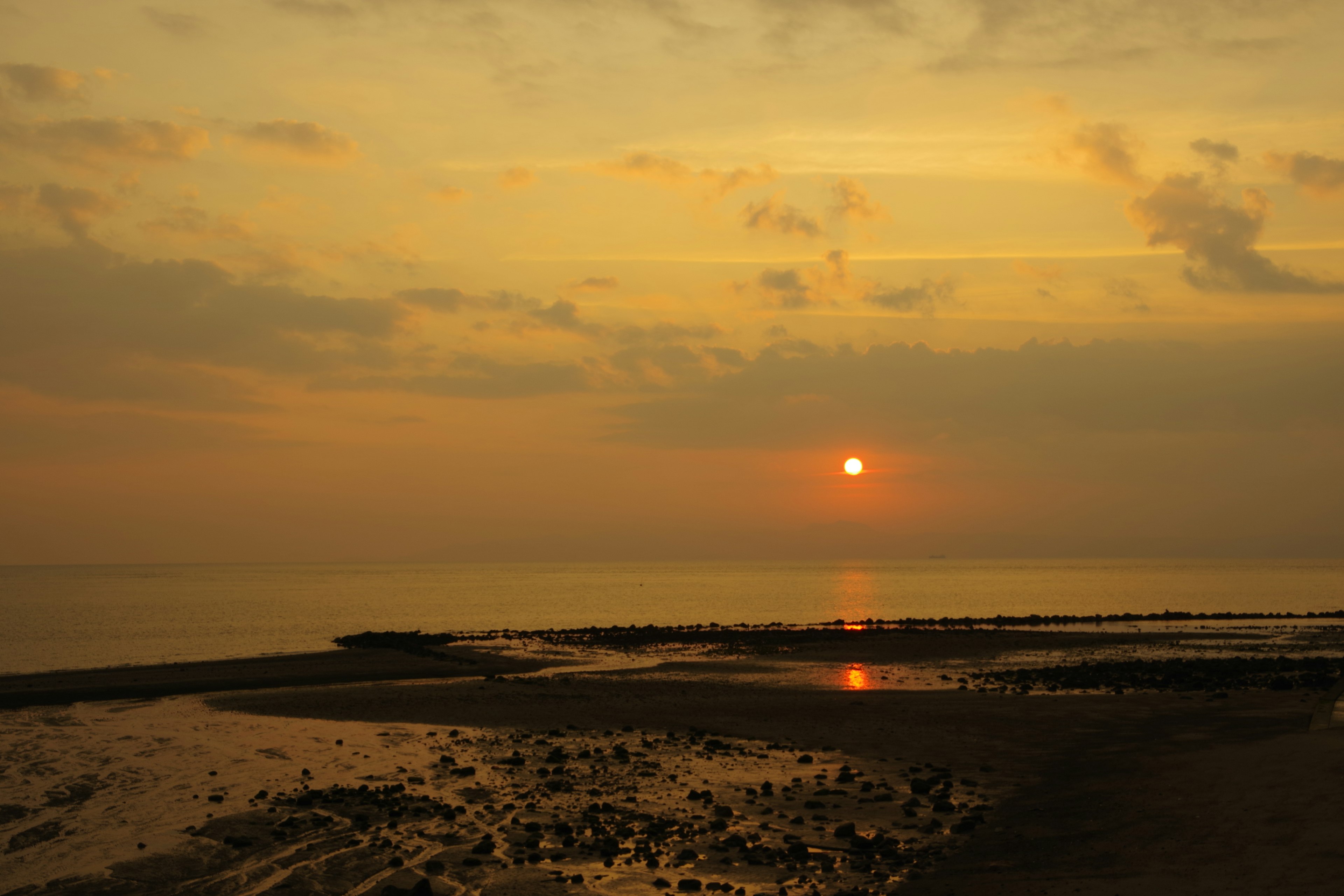 Sonnenuntergang über dem Ozean mit ruhiger See und bewölktem Himmel