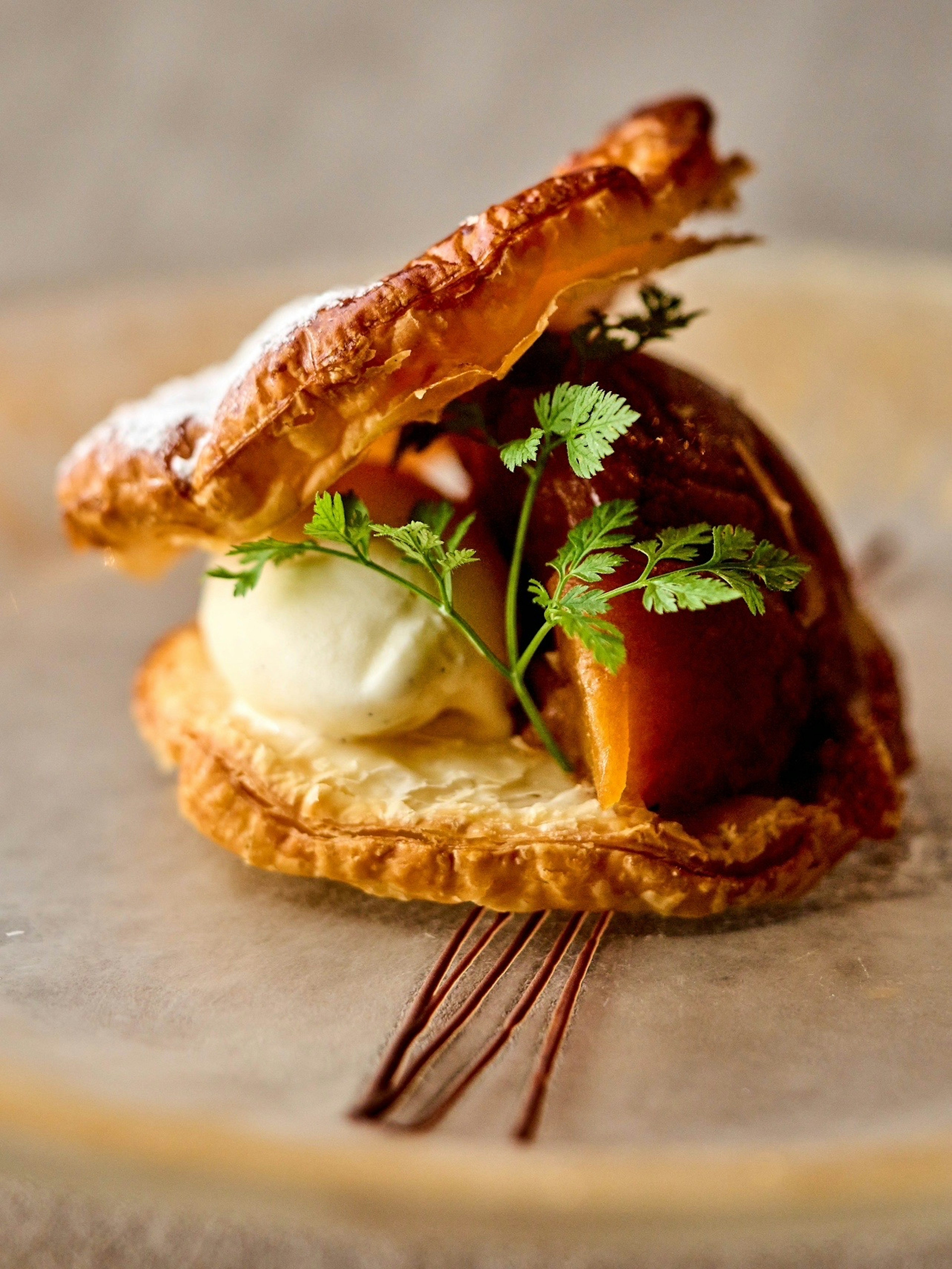 Postre con masa hojaldrada, helado y decorado con hierbas frescas