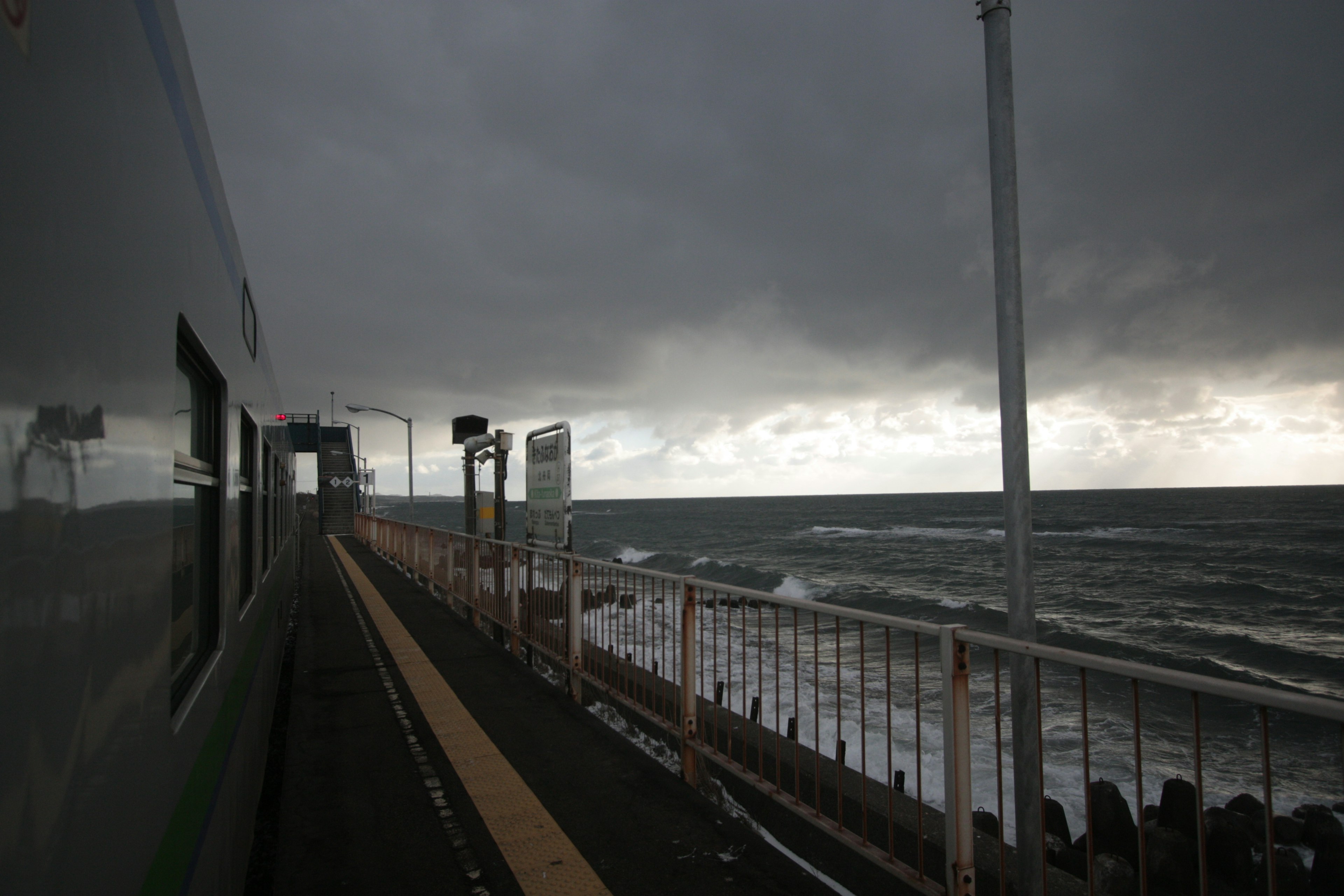 海と列車のプラットフォームが見える曇り空の風景