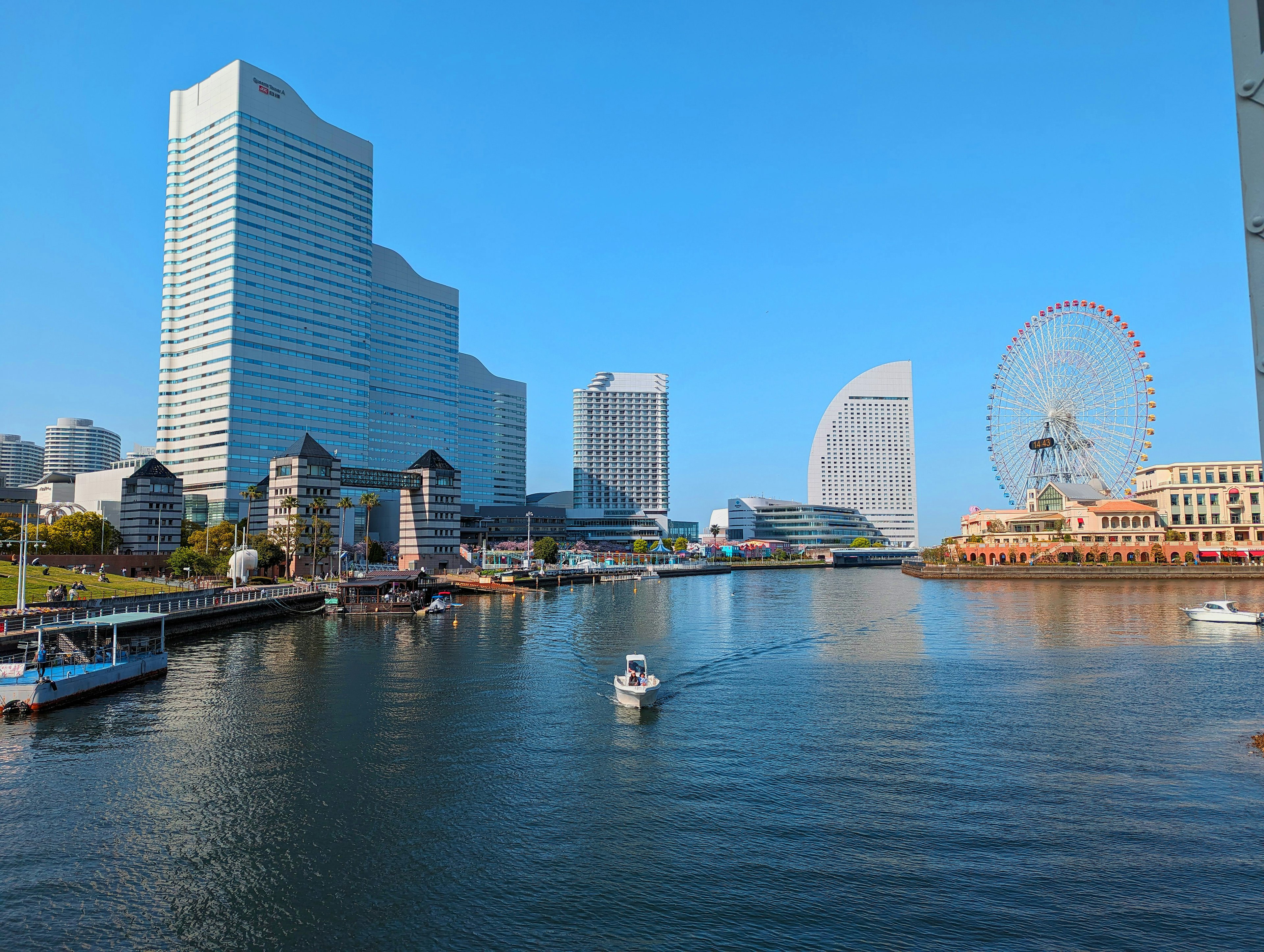 Yokohama skyline with high-rise buildings and waterfront small boat gliding on water clear blue sky