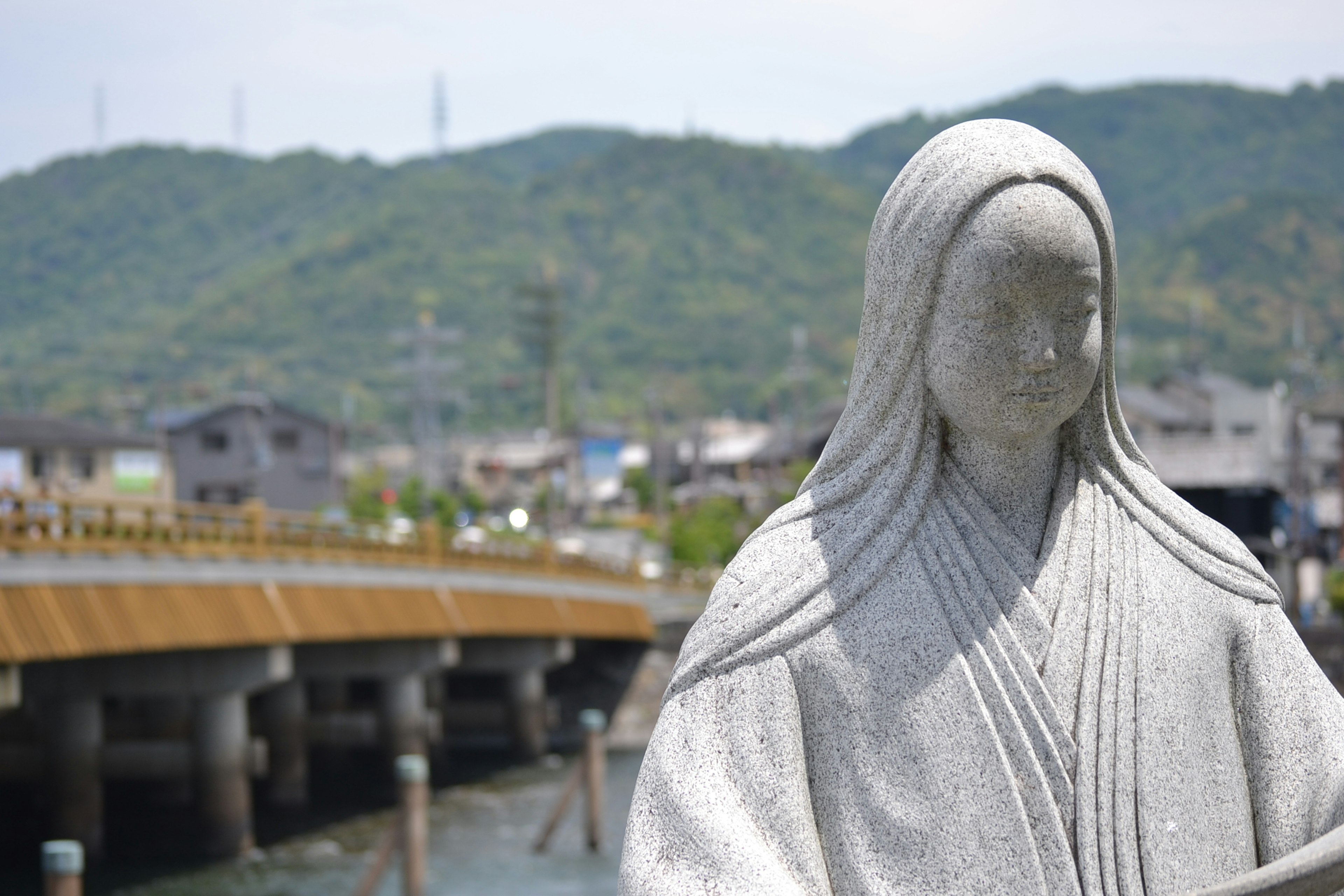 Statue en pierre blanche se tenant au bord de la mer avec des montagnes en arrière-plan