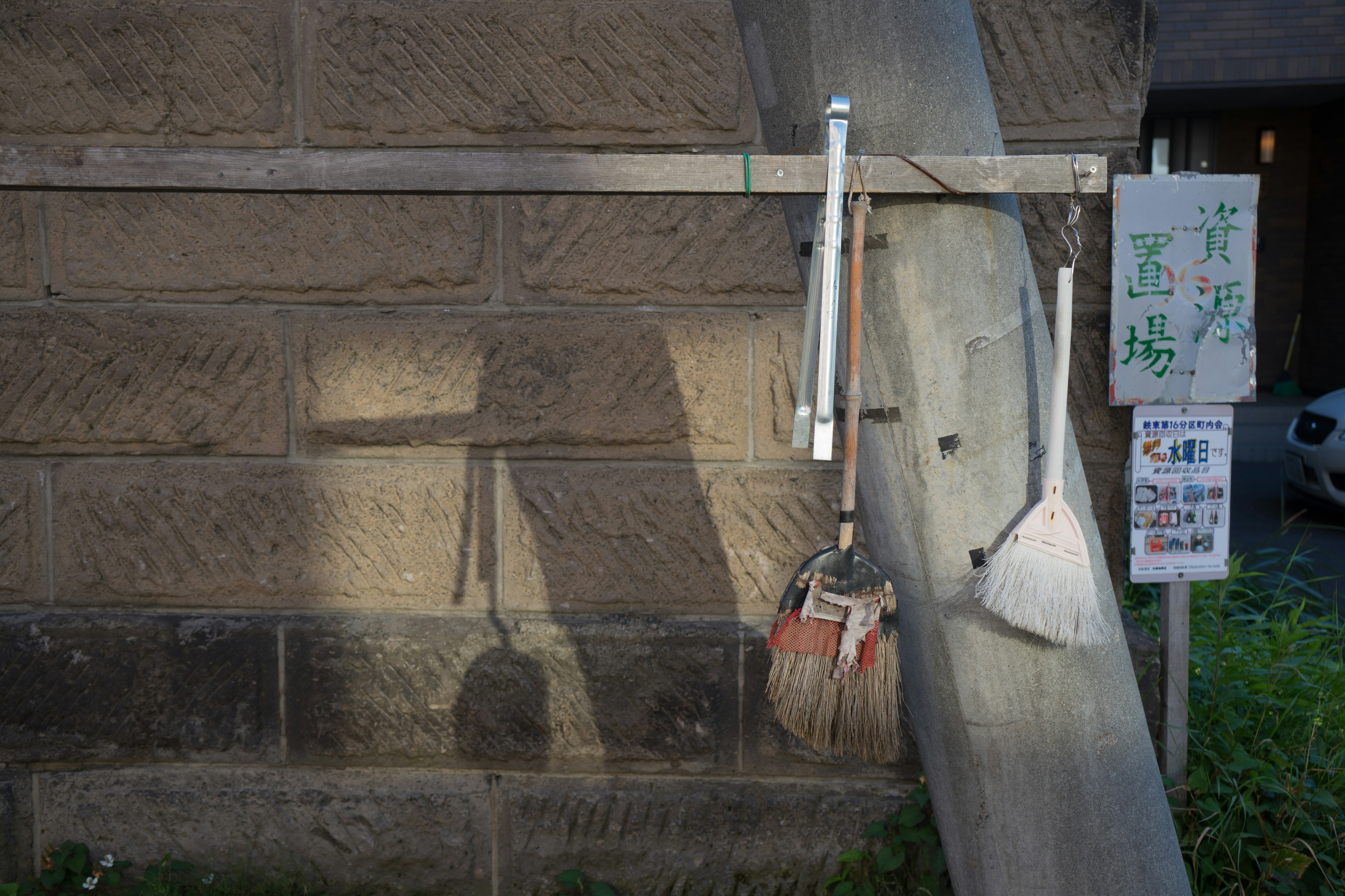 Cleaning tools and a sign hanging on a stone wall