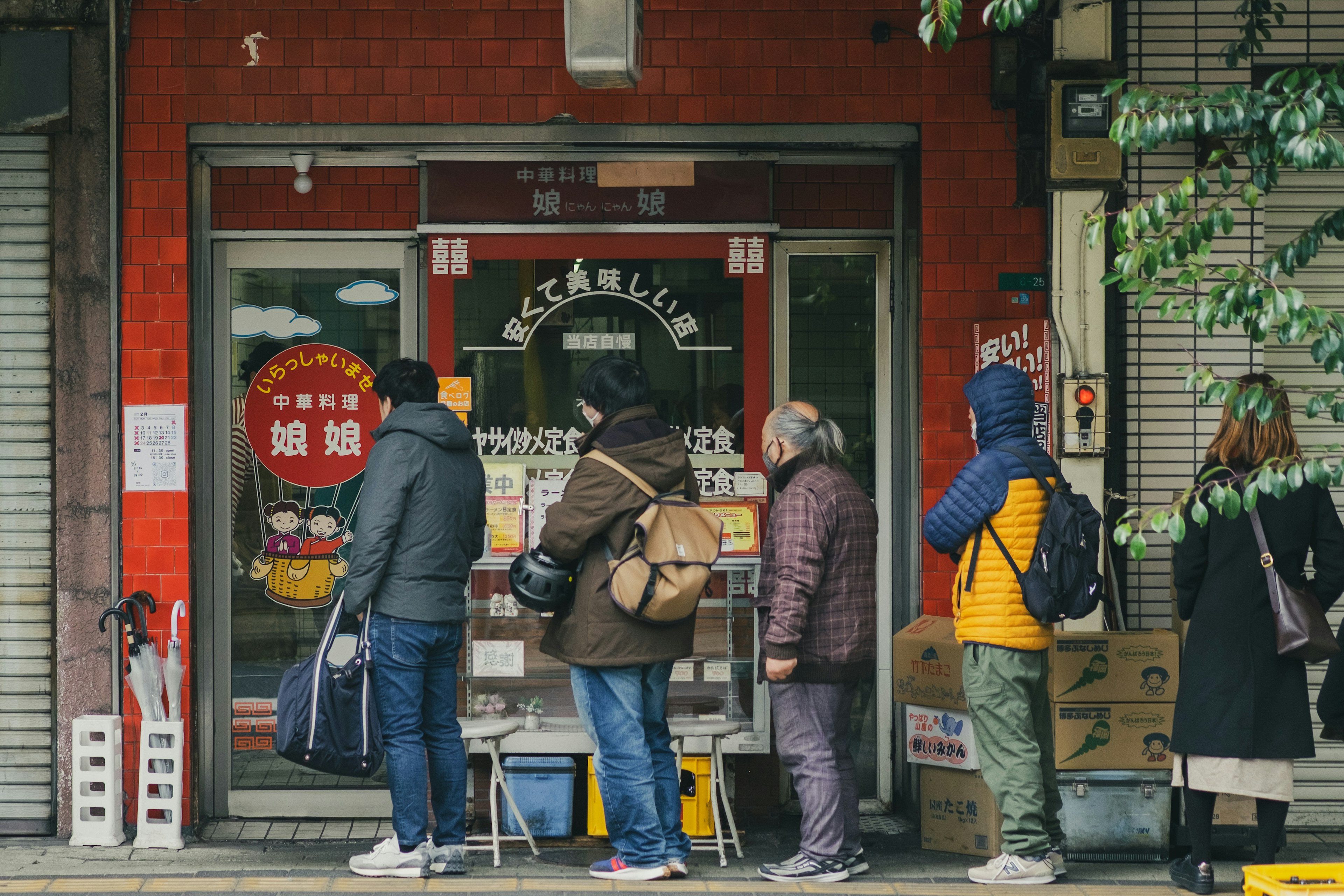 Personnes faisant la queue devant un magasin avec un mur rouge