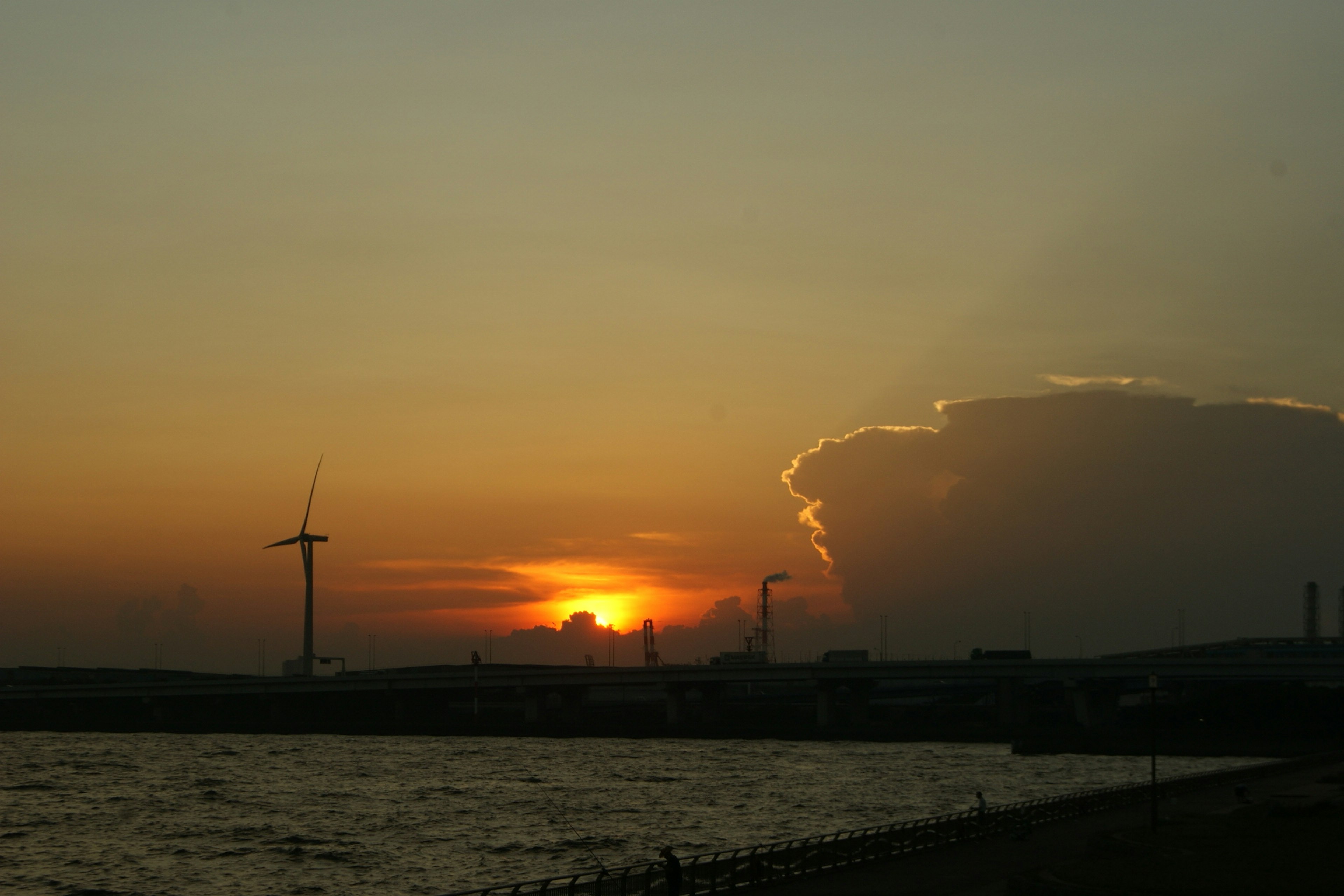 Paesaggio costiero con tramonto turbina eolica e nuvole sorprendenti