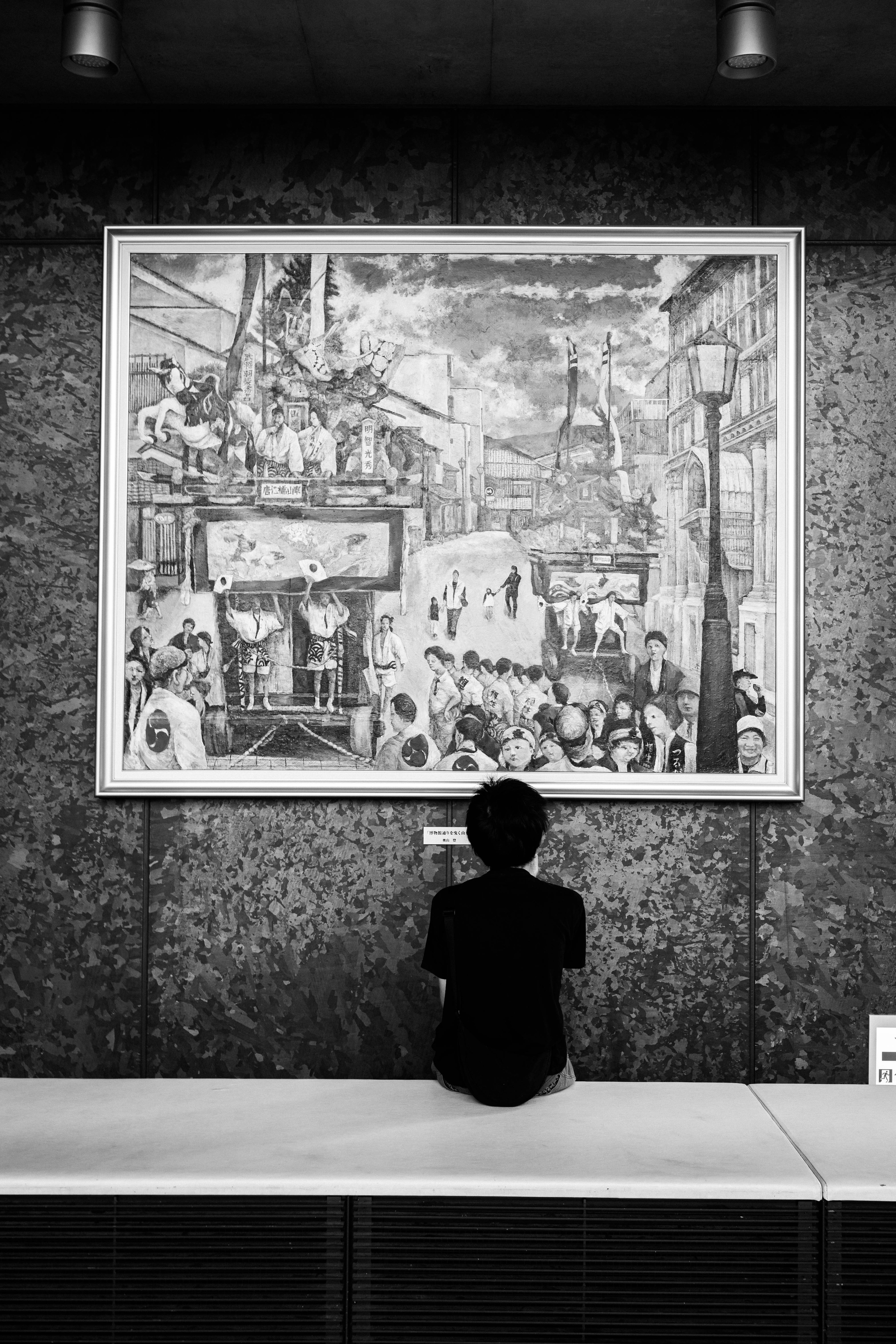 Personne regardant une peinture en noir et blanc dans une galerie d'art