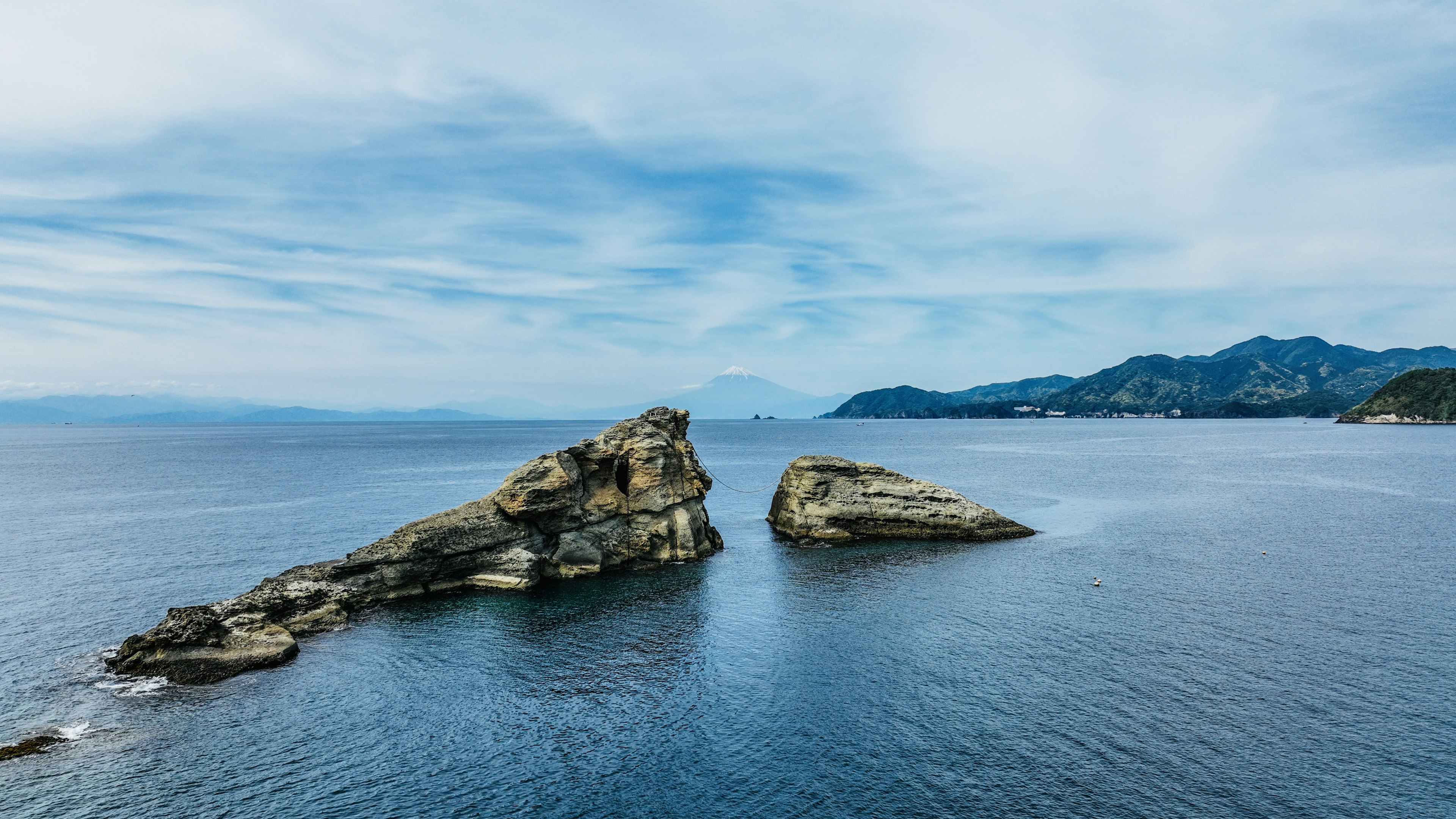 Pemandangan dengan dua formasi berbatu di laut biru di bawah langit yang cerah