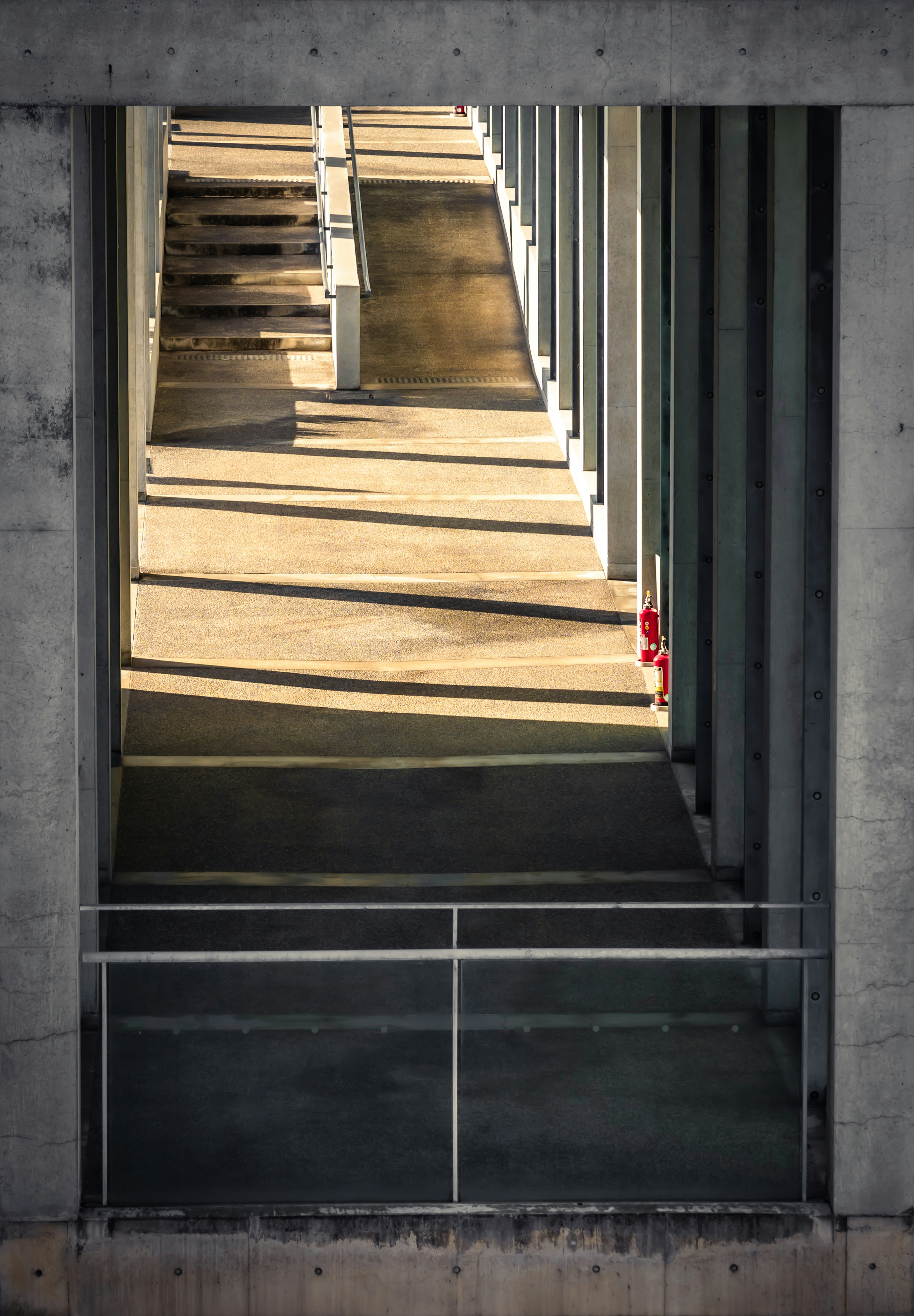 Lorong modern dengan pilar beton dan bayangan di lantai