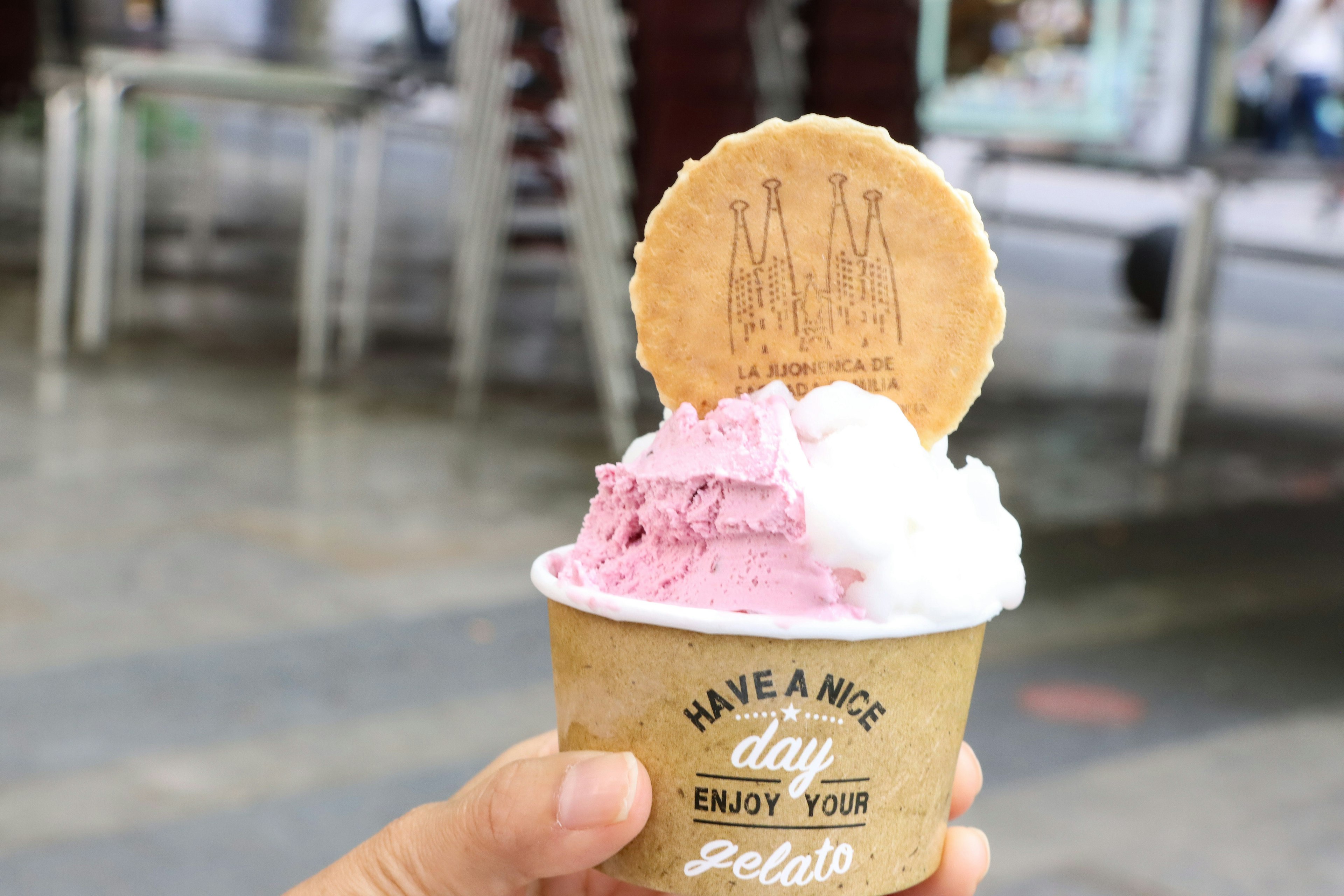 Sebuah cangkir es krim dengan gelato merah muda dan putih di atasnya terdapat kue