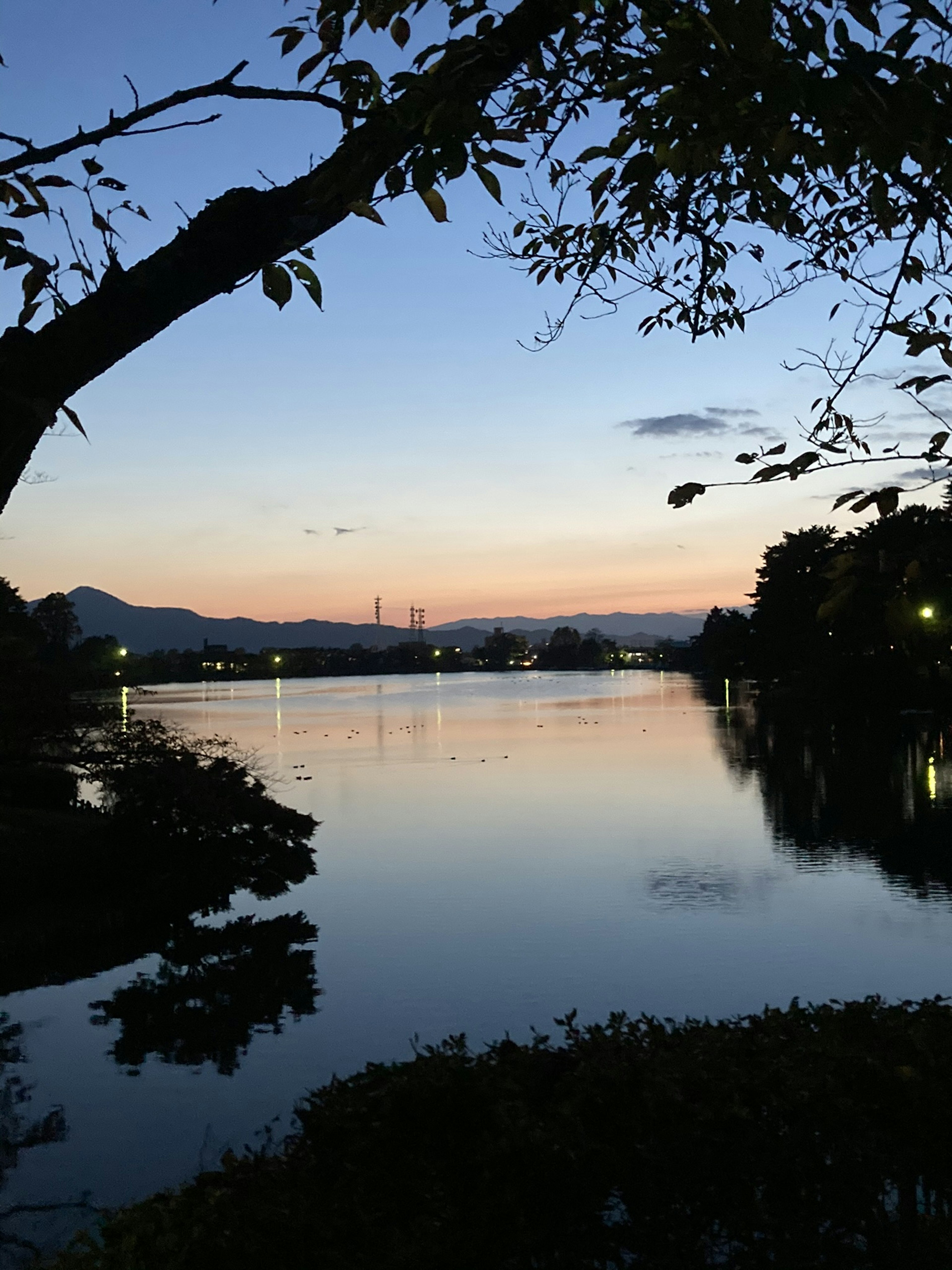 Lago sereno reflejando el cielo del crepúsculo y el paisaje circundante