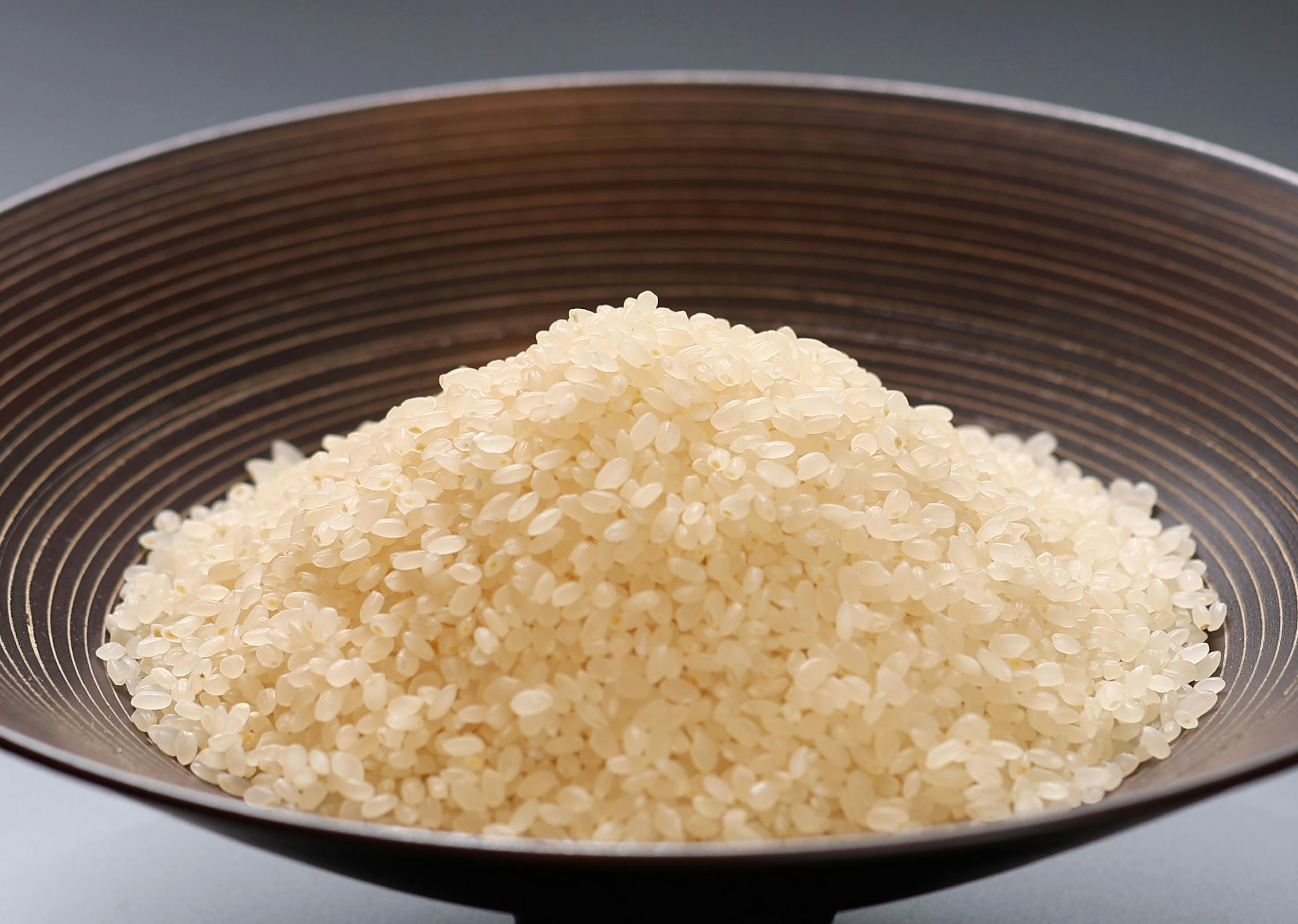 A mound of white rice in a brown bowl