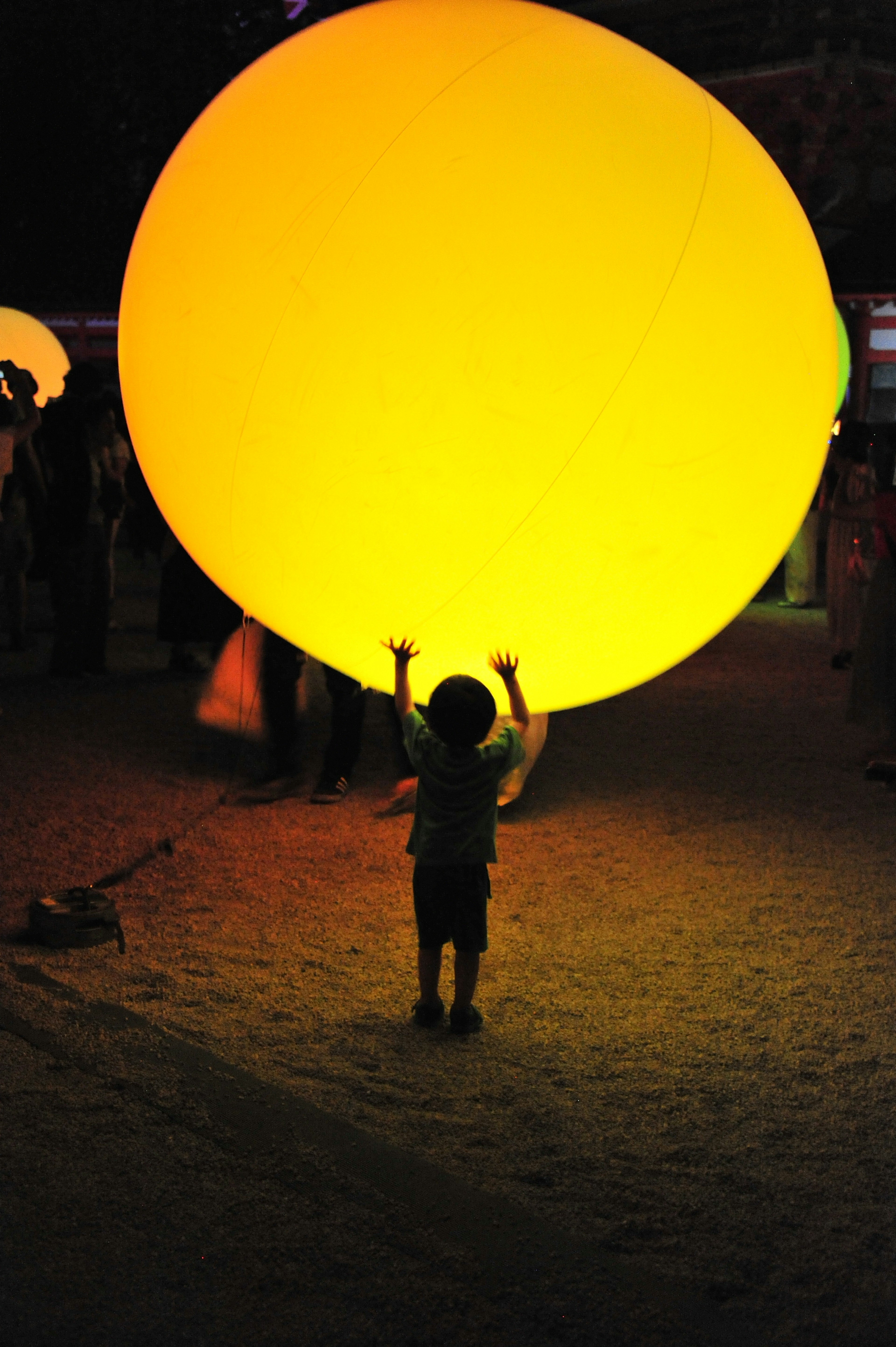 Kind hält einen großen gelben Ballon in einer nächtlichen Umgebung