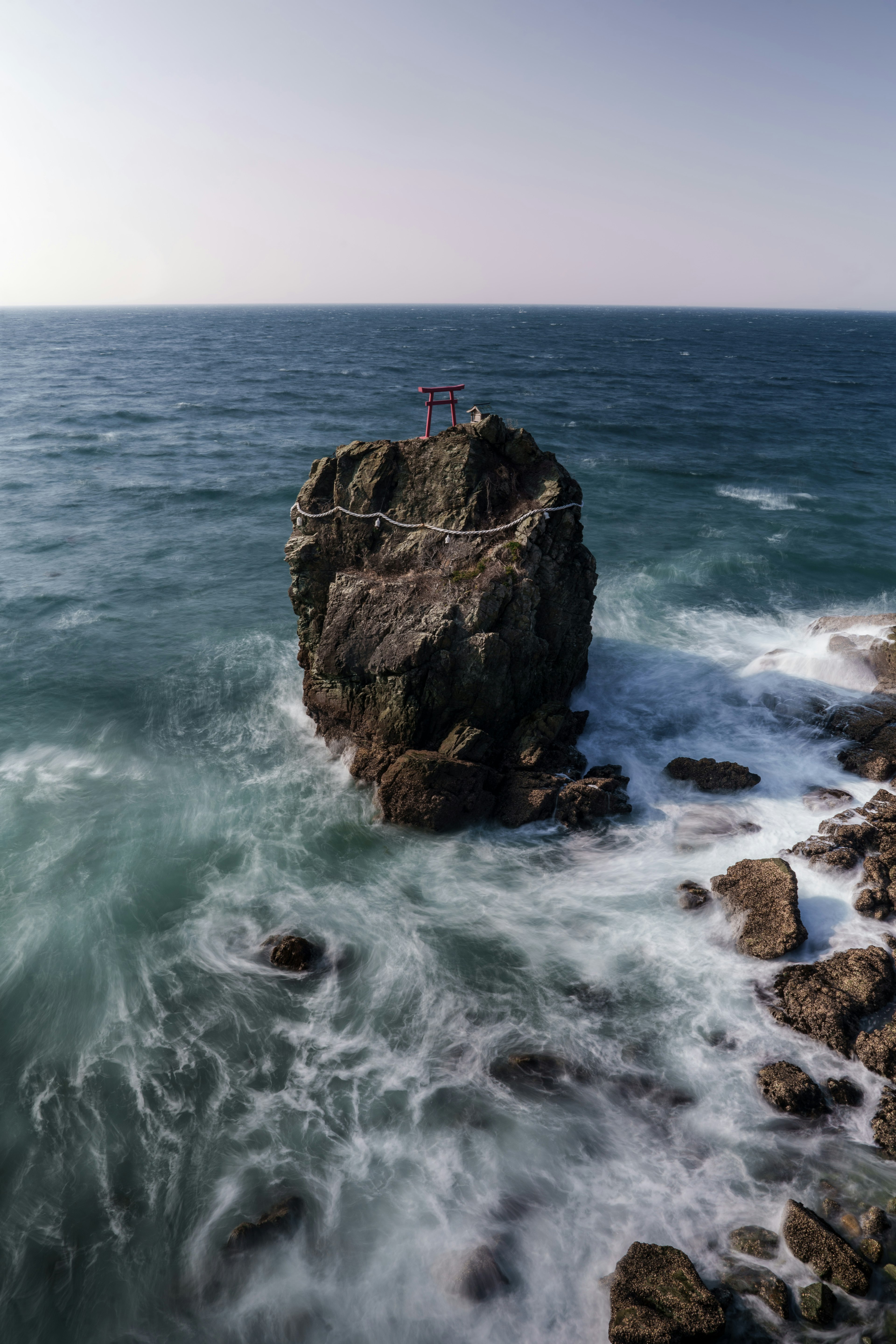 Un grand rocher entouré de vagues océaniques bleues